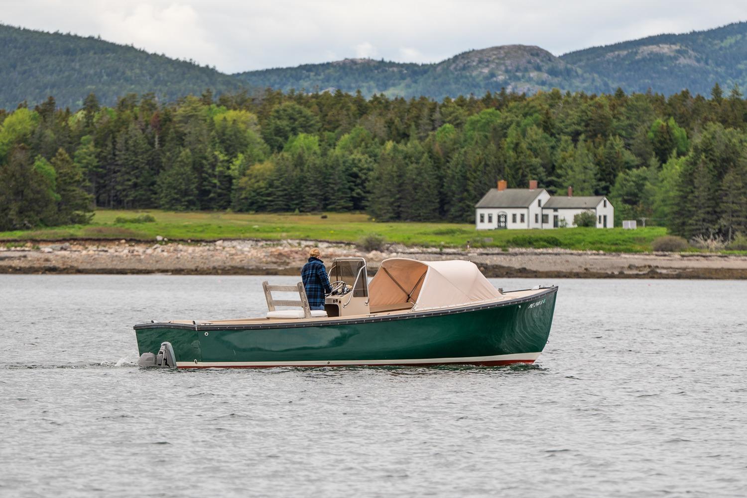 1989 Ellis 24 Open boat cruising on a scenic lake with forested hills in the background.