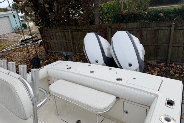 2002 Regulator 26 Forward Seating boat with dual outboard engines, docked near a wooden fence.