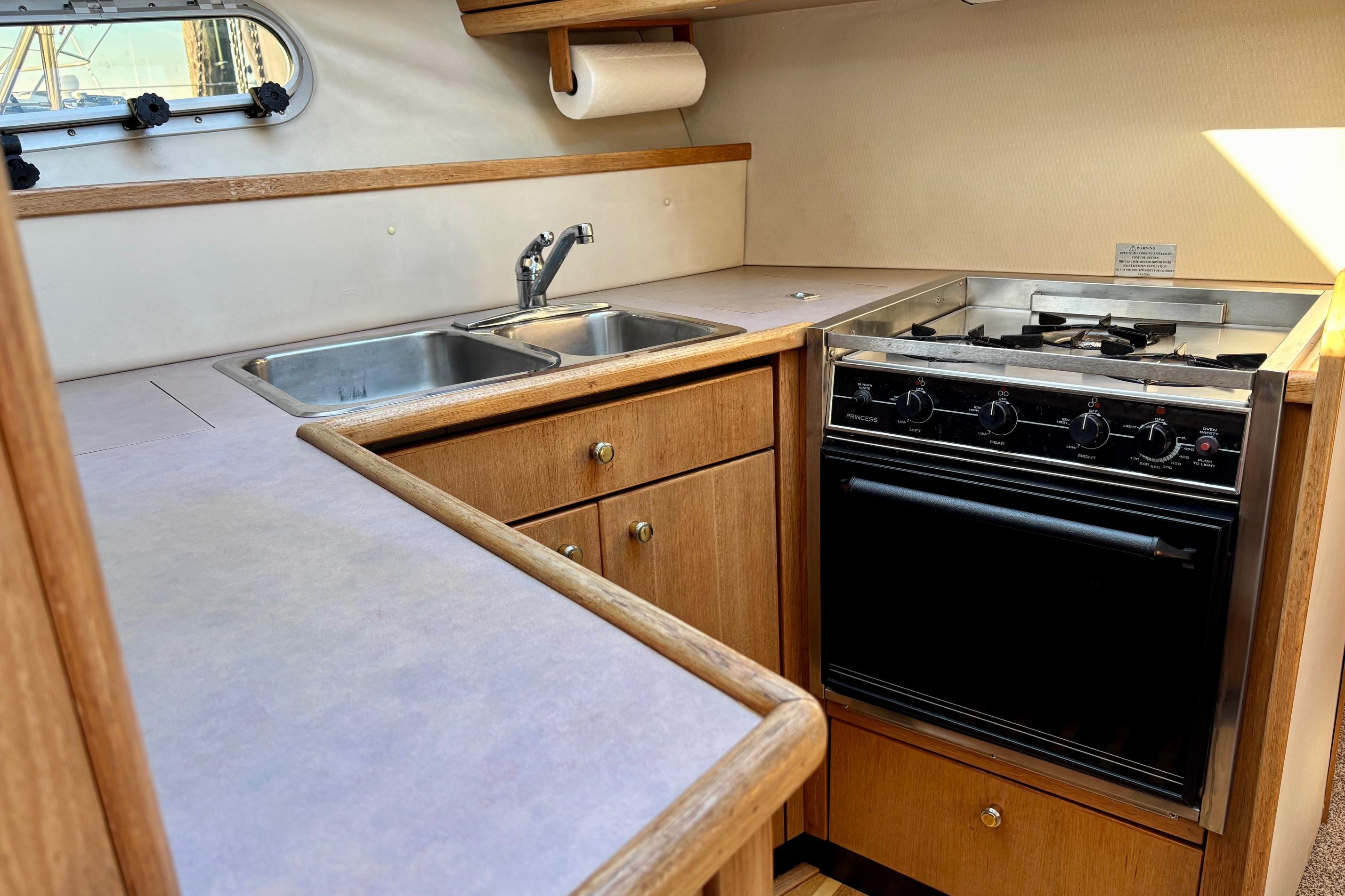 1998 Bayliner 3388 Command Bridge Motoryacht kitchen with stove, double sink, and wooden cabinetry.