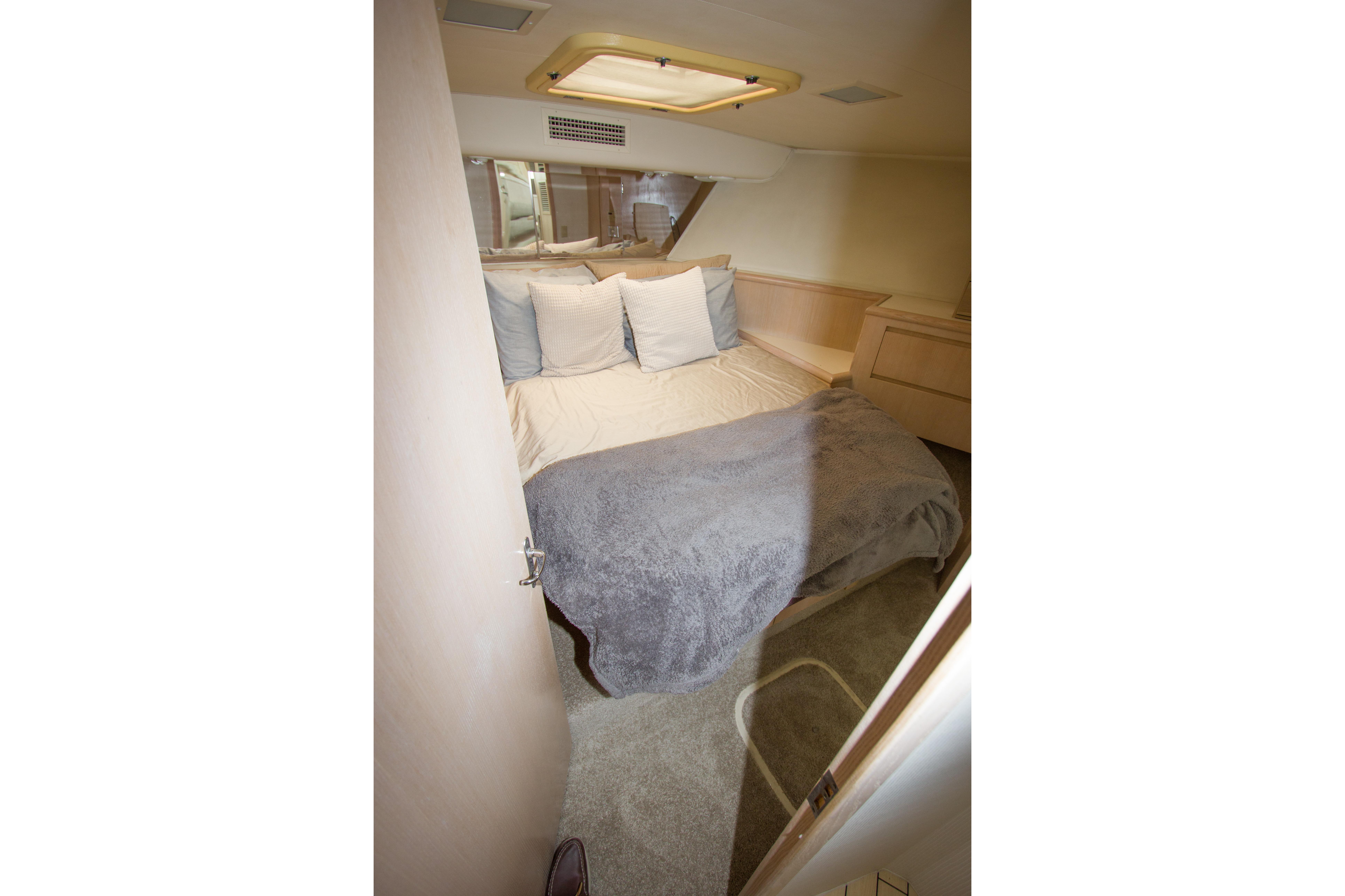 Cozy bedroom in 1994 Hatteras 52 Cockpit Motor Yacht with plush bedding and soft lighting.