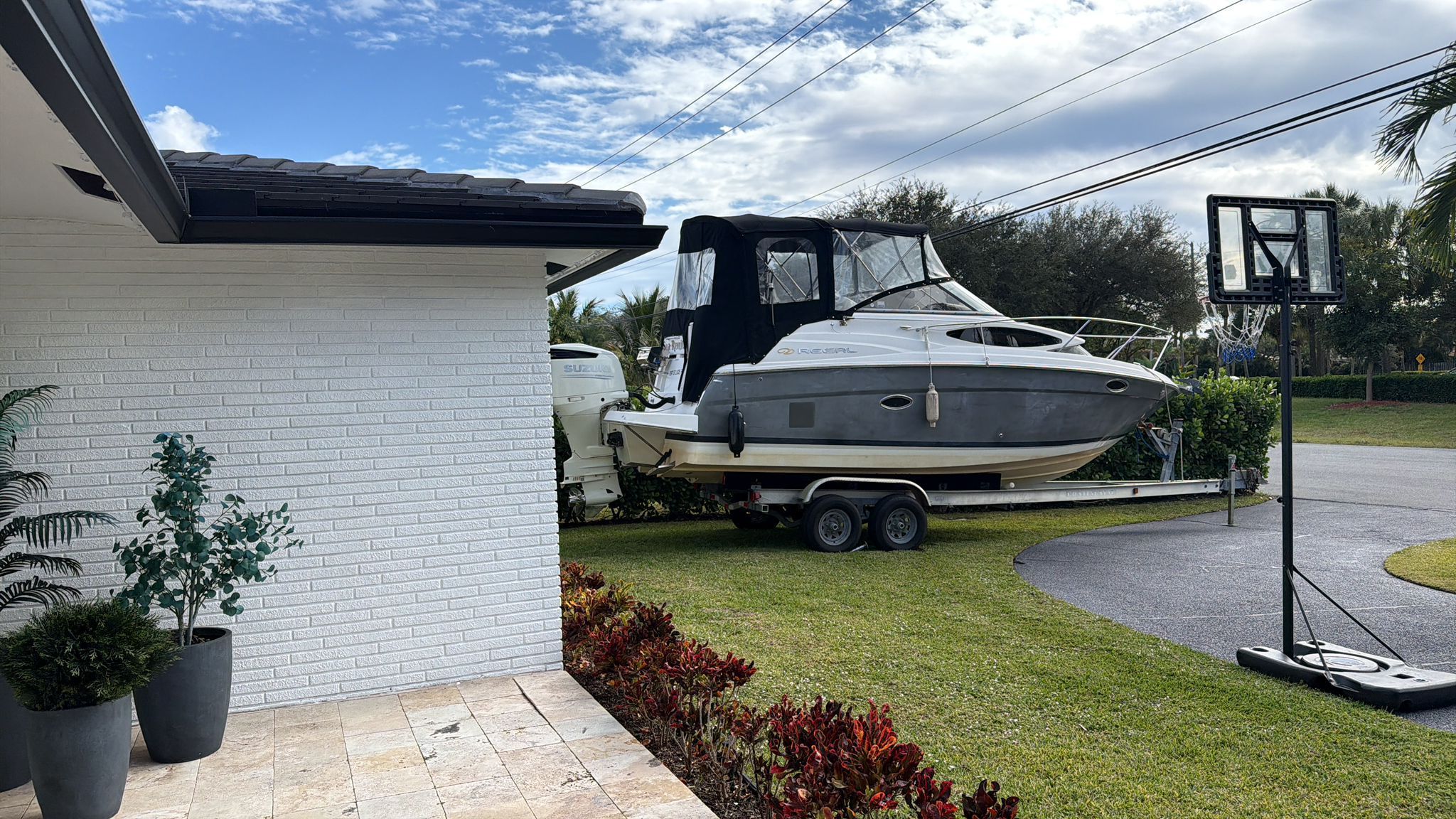 A 2008 Regal 2565 Window Express boat on a trailer beside a house.
