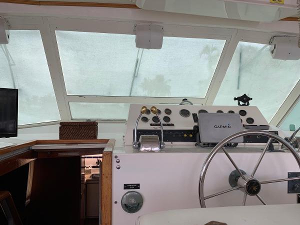1987 Bertram Motoryacht helm with steering wheel, Garmin navigation, and control panel.
