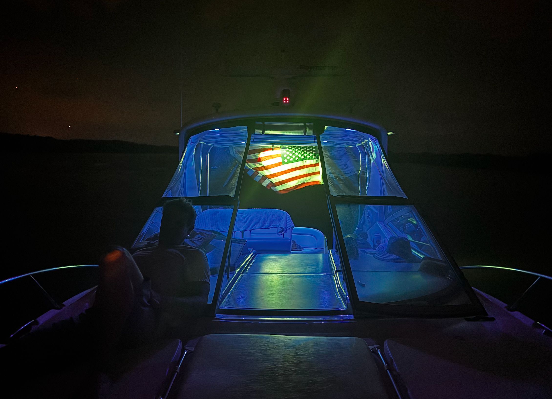 Sea Ray Sundancer 310 boat at night with illuminated US flag.