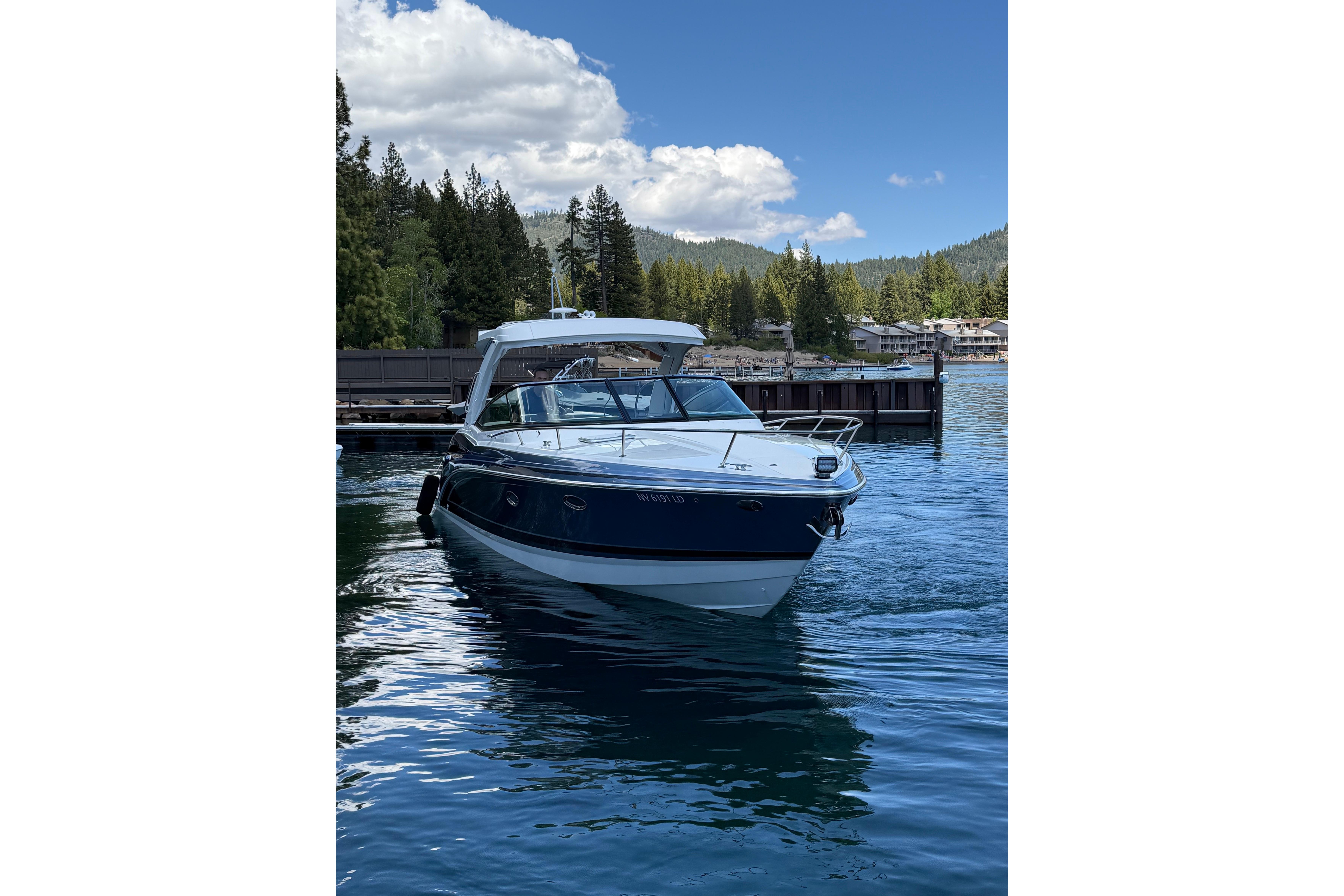 2021 Formula 350 Sun Sport boat docked on a serene lake with forested hills.
