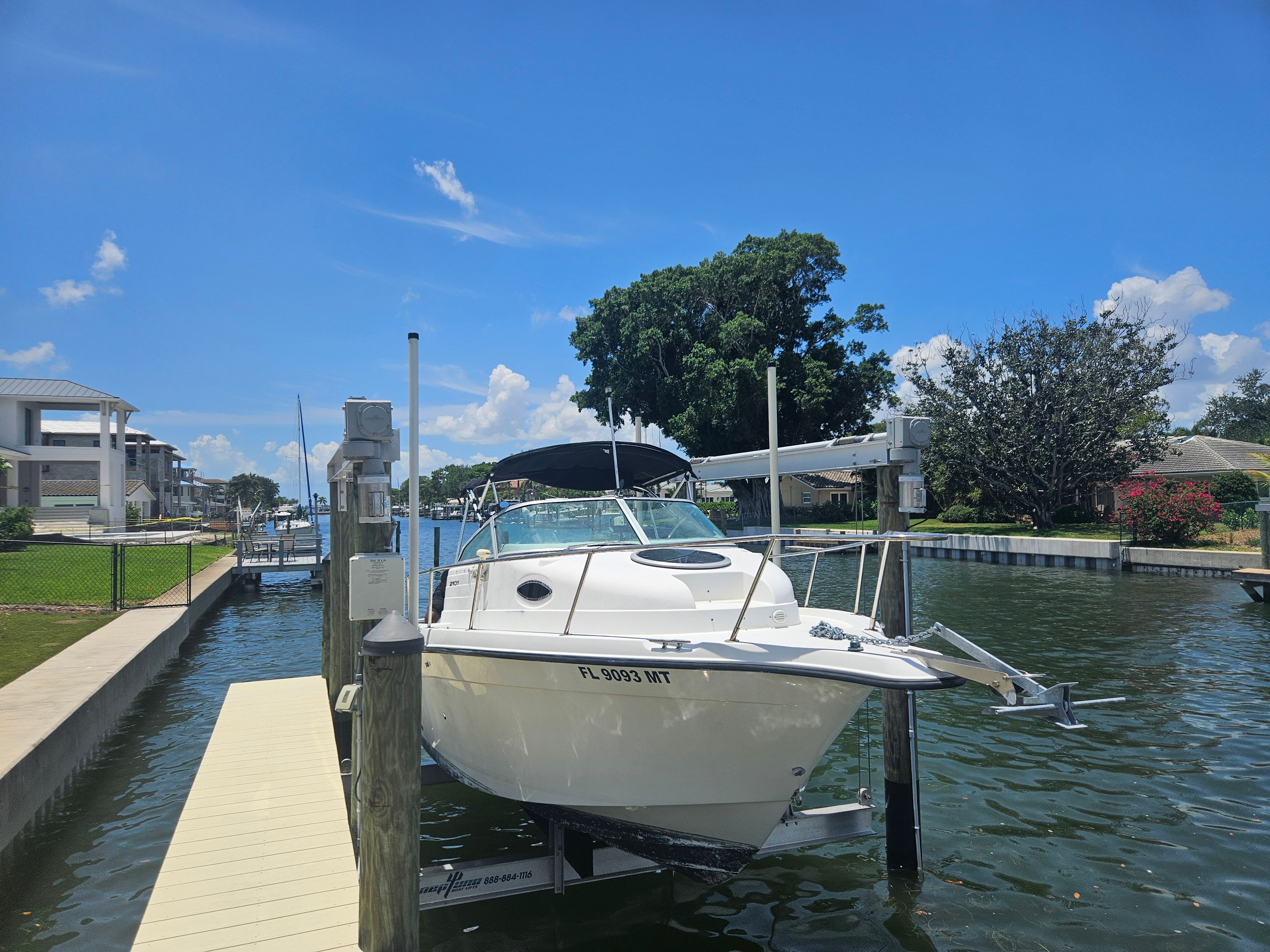 A 2004 Seaswirl Striper 2101 Walkaround O/B is docked in a calm harbor.