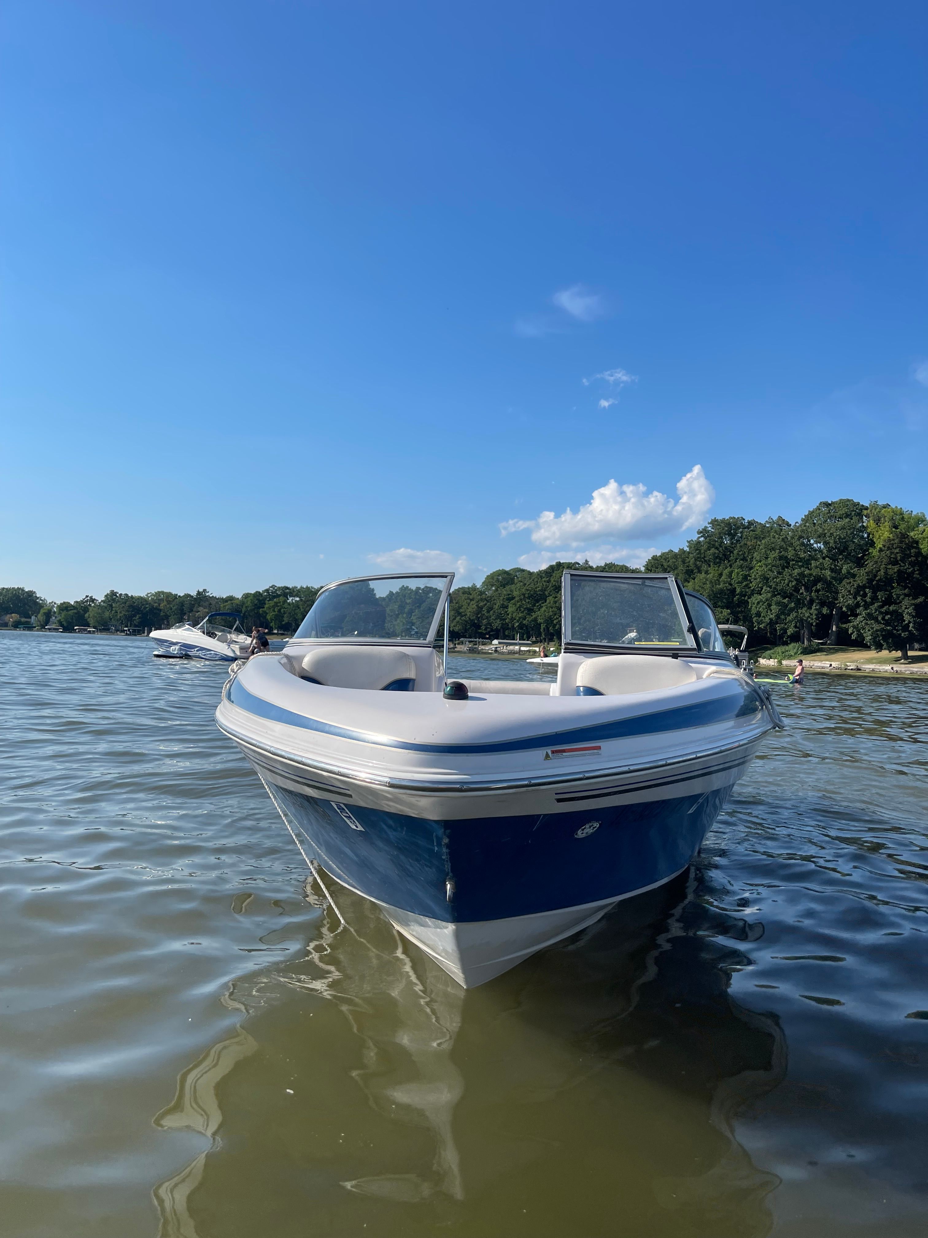 2005 Tahoe Q6 Sport on the water with clear skies and trees in the background.