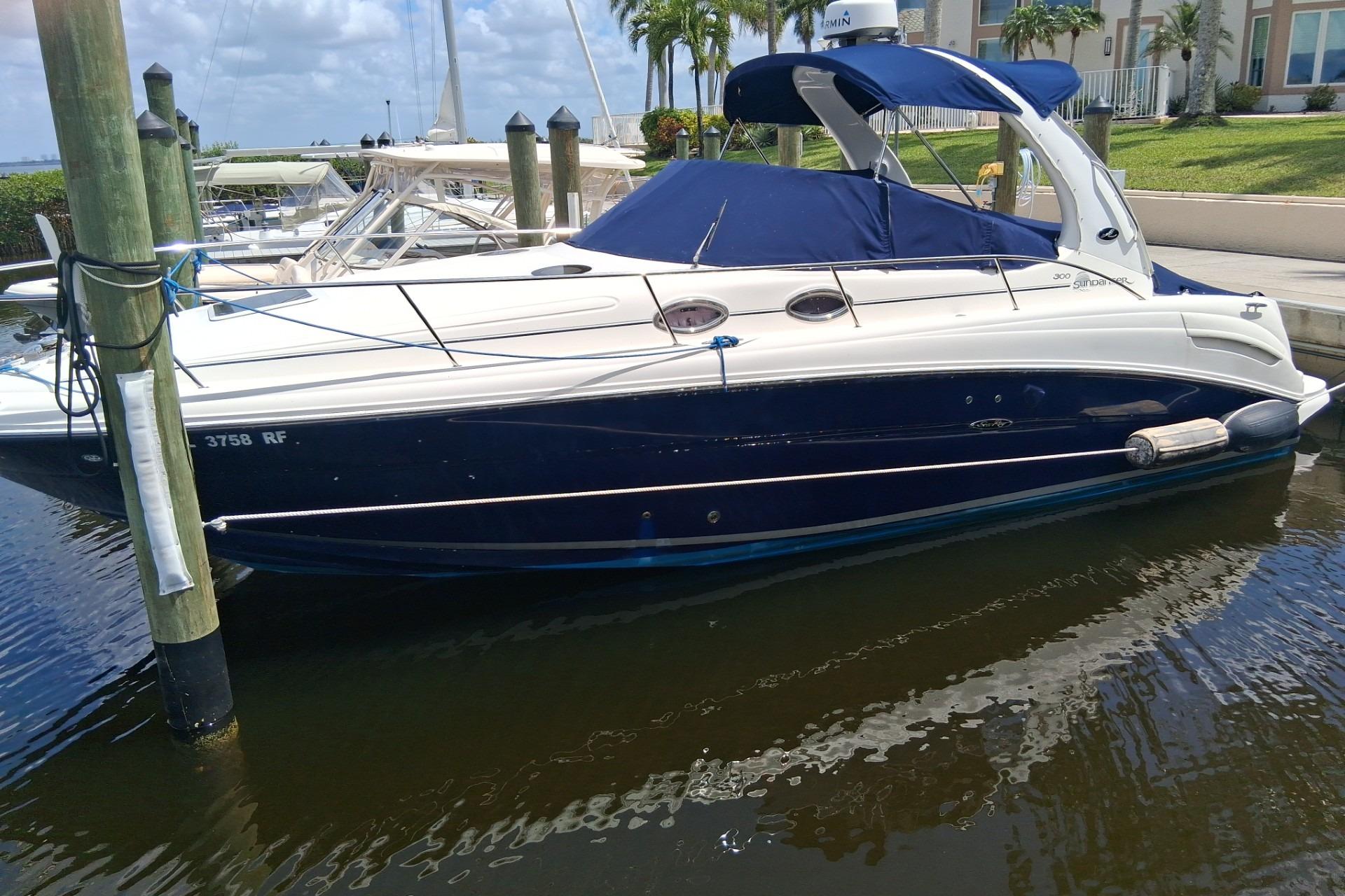 2005 Sea Ray 300 Sundancer docked at marina, featuring sleek design and blue canopy.