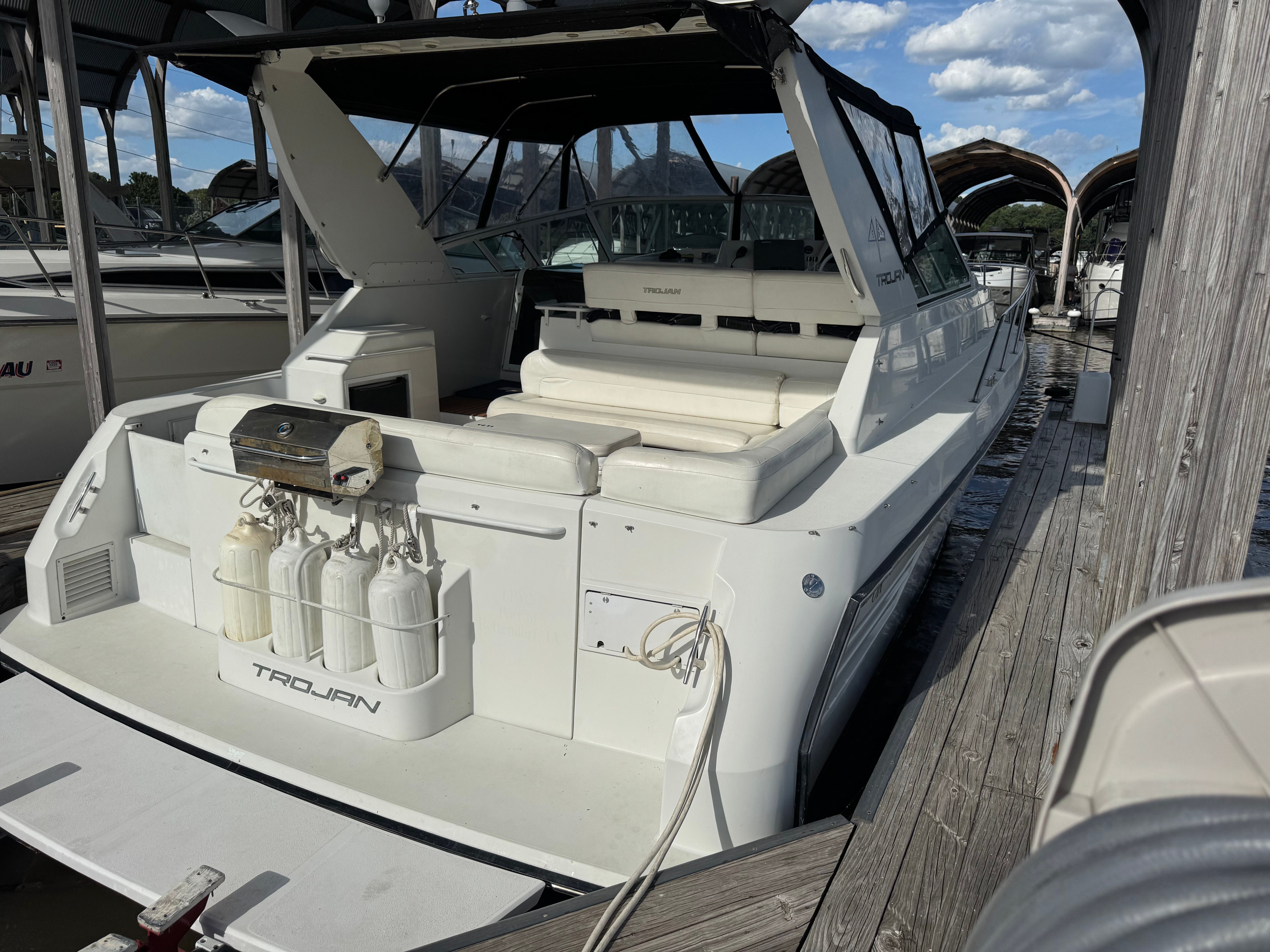 A white 1995 Trojan 390x docked, featuring an open cockpit and several fenders.