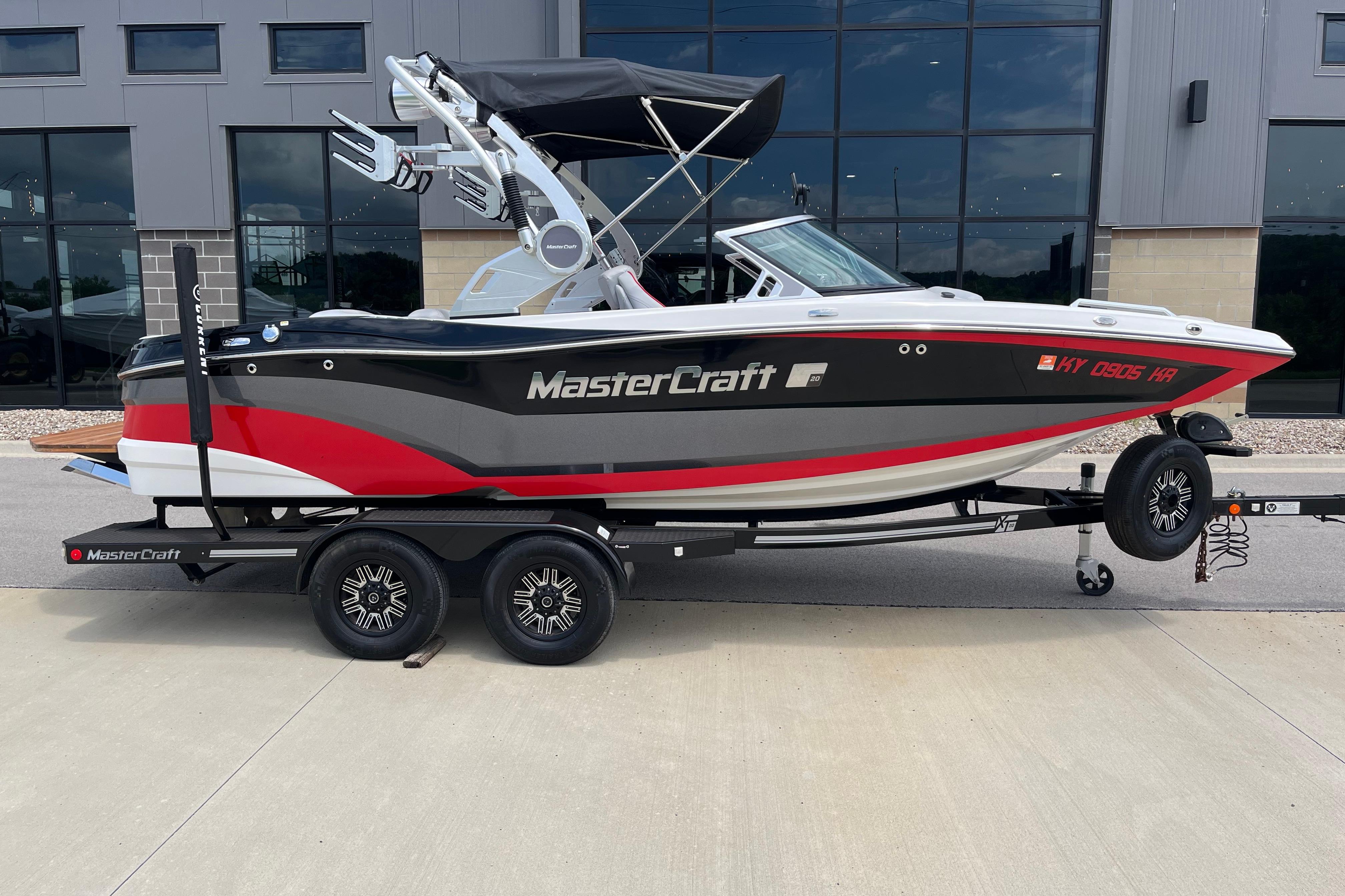2019 MasterCraft XT20 boat on trailer, parked outside a modern building.