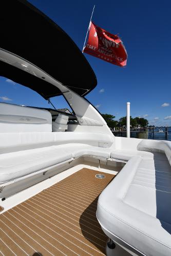 1997 Sea Ray 400 Sundancer yacht with white seating and red flag, docked under clear blue sky.