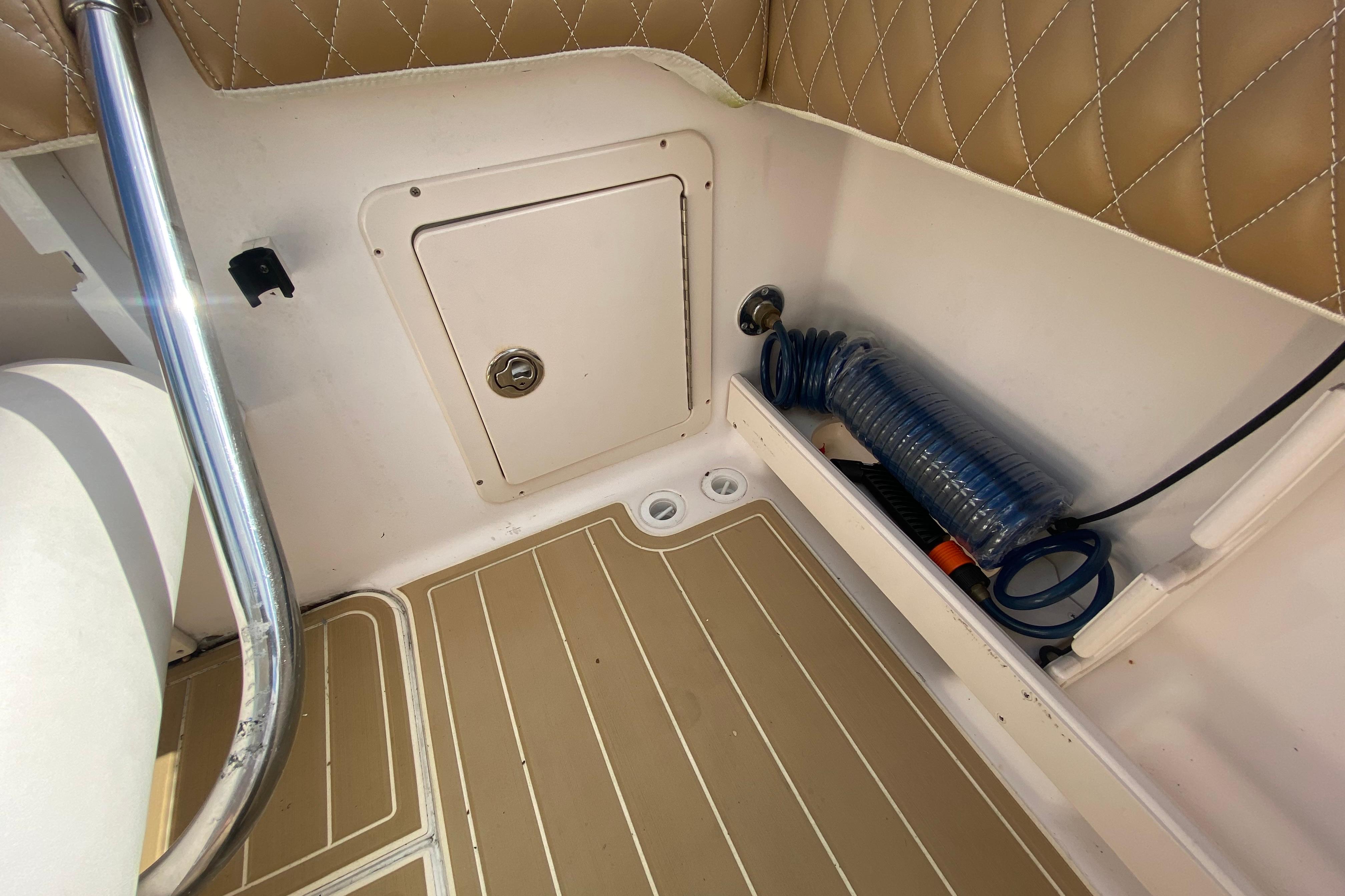 2004 Grady-White Canyon 283 boat interior with storage compartment and coiled hose.