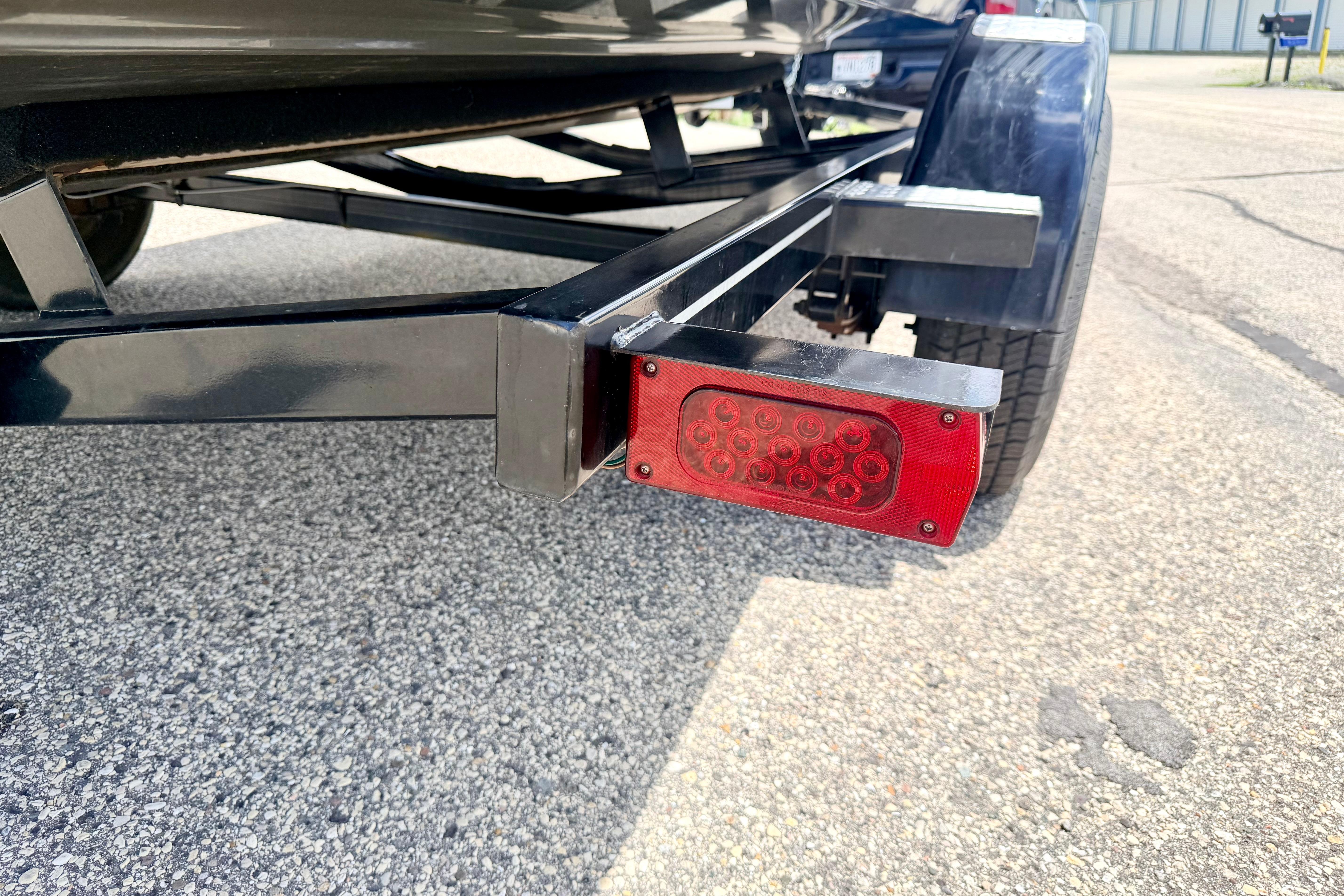 Trailer light and wheel of a 2018 Glastron GT 185 boat on pavement.