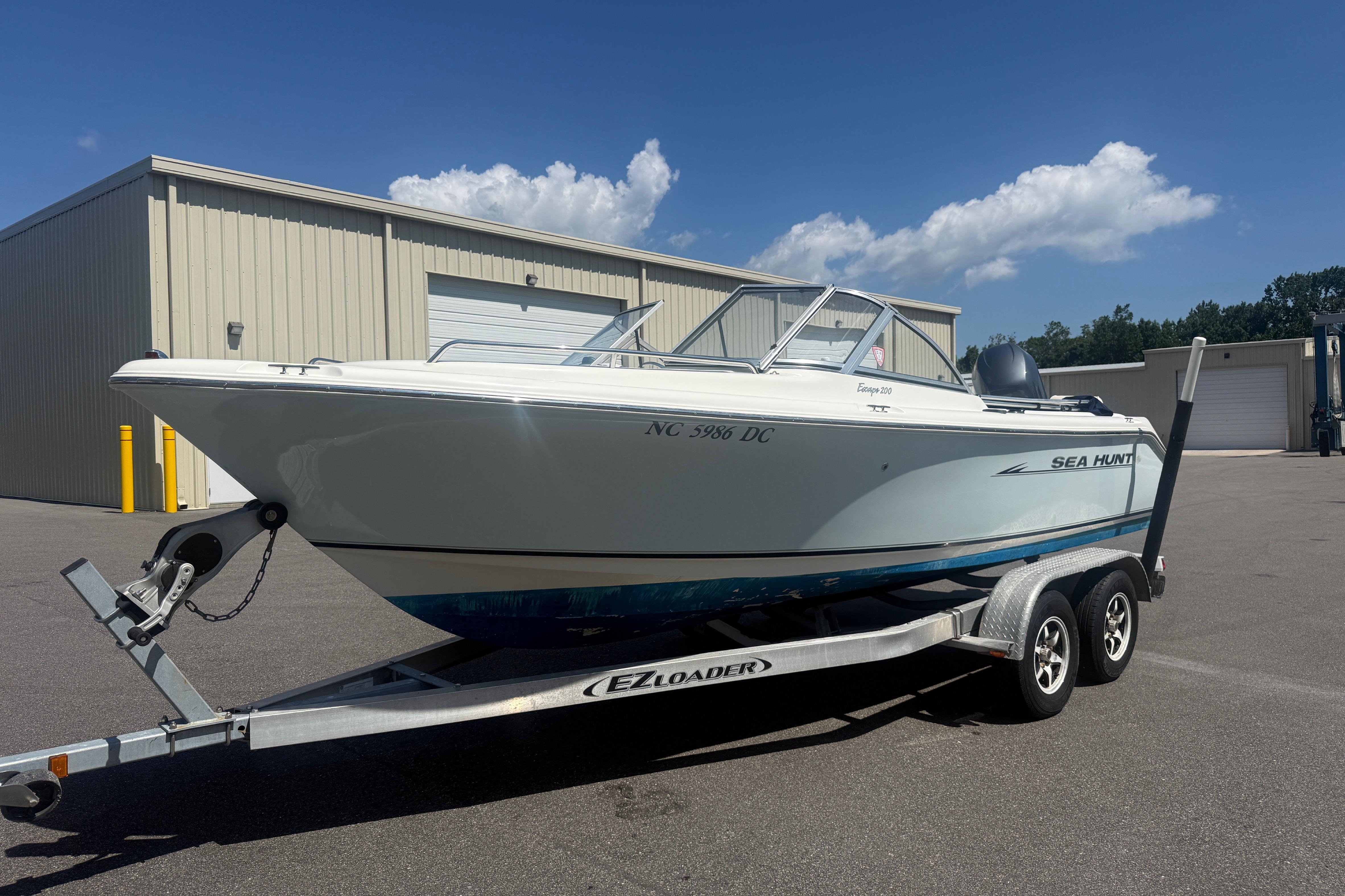 2006 Sea Hunt Escape 200 boat on trailer, parked outside industrial building.