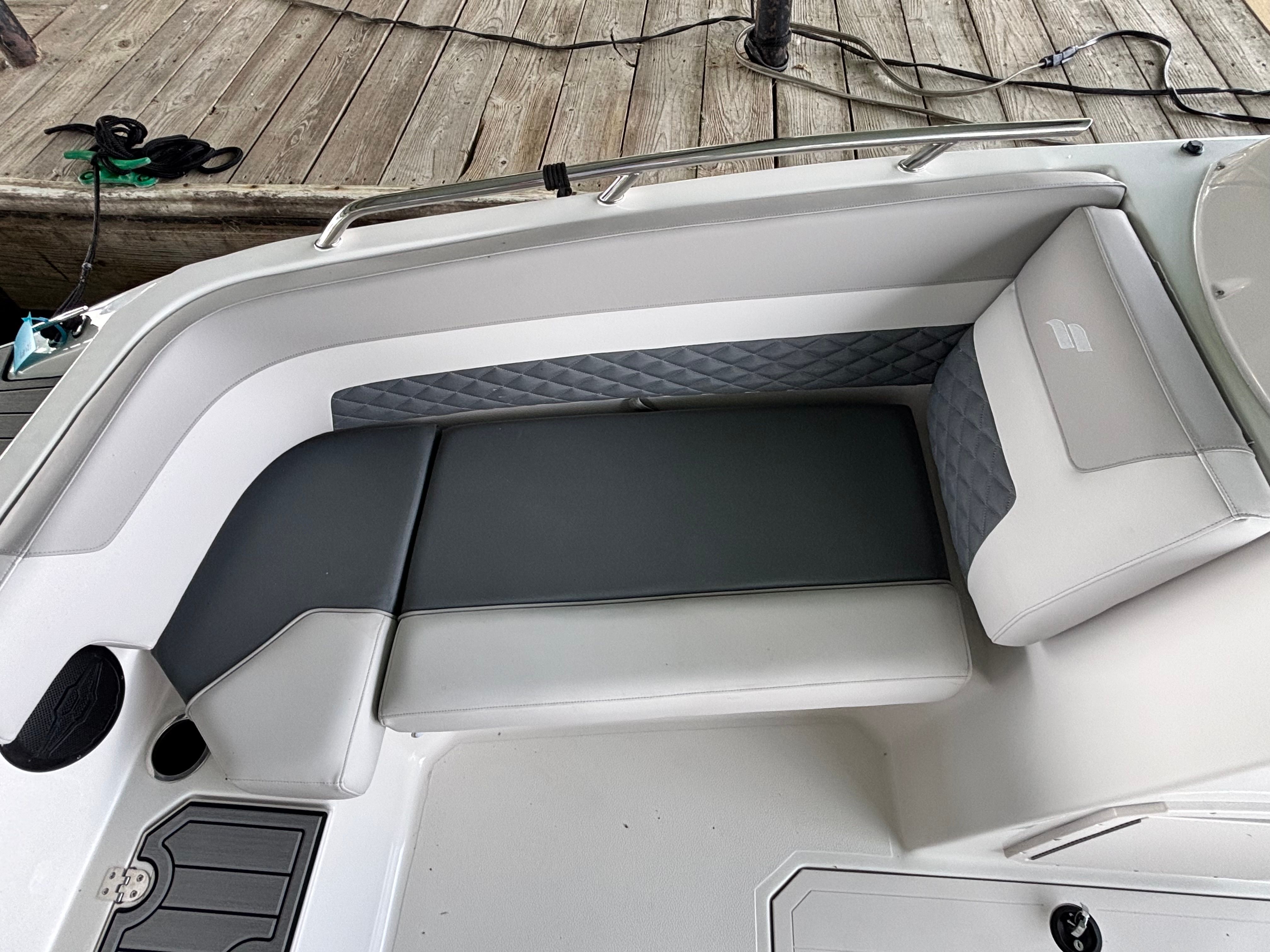 The image shows a gray and white seating area on a boat docked at a wooden pier.