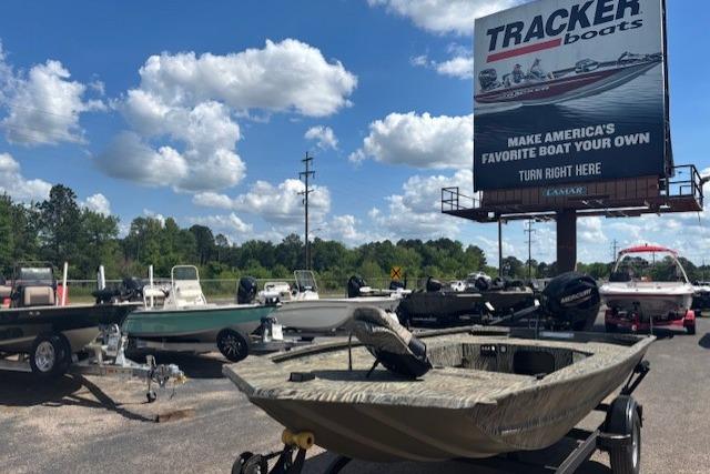 Outdoor display of Tracker Grizzly 1654 T Sportsman boats with promotional billboard in background.