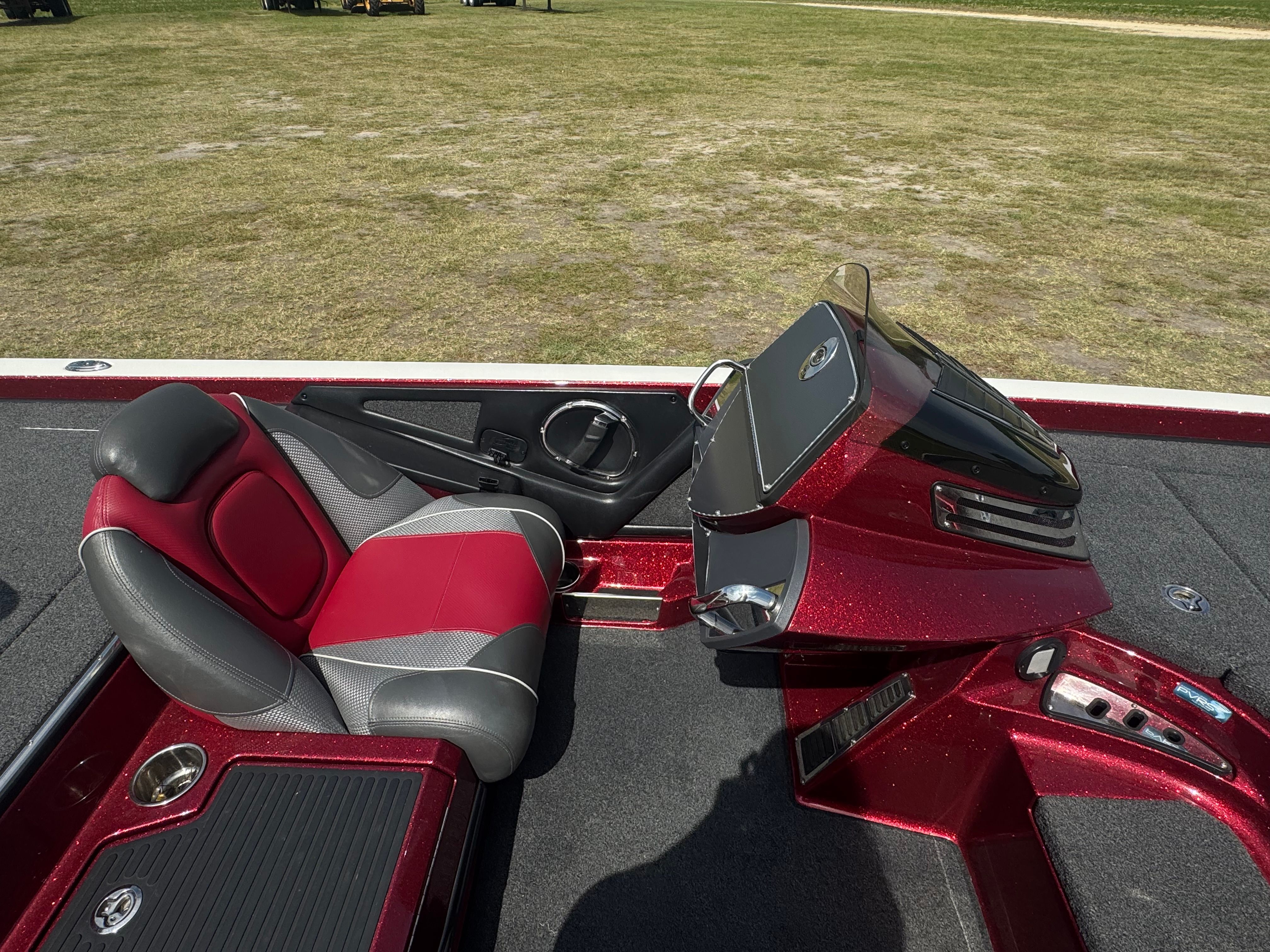 A red Ranger boat with gray and red seats on a grassy area.