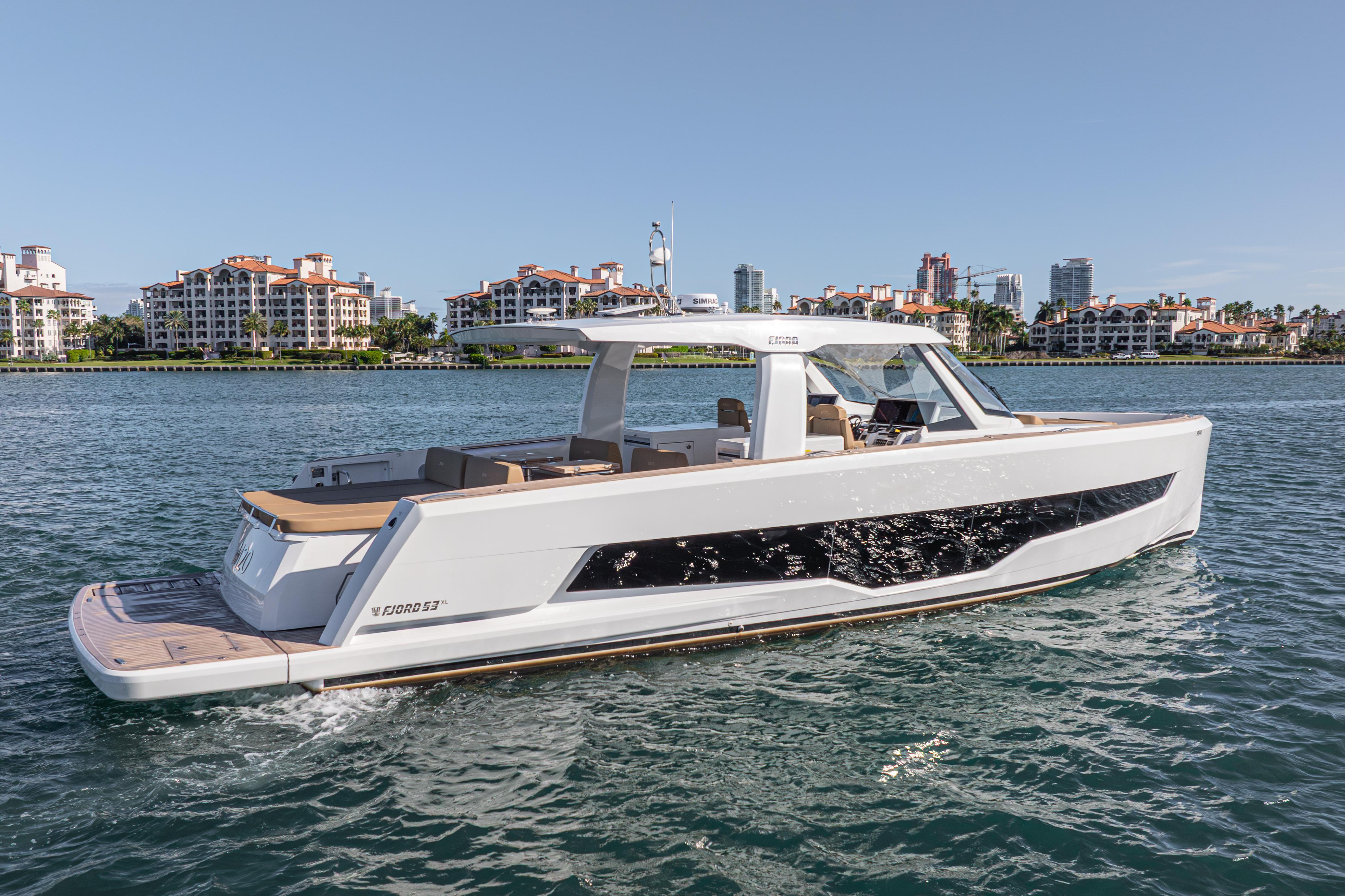 2024 Fjord Boats 53XL cruising on water with luxury waterfront buildings in the background.