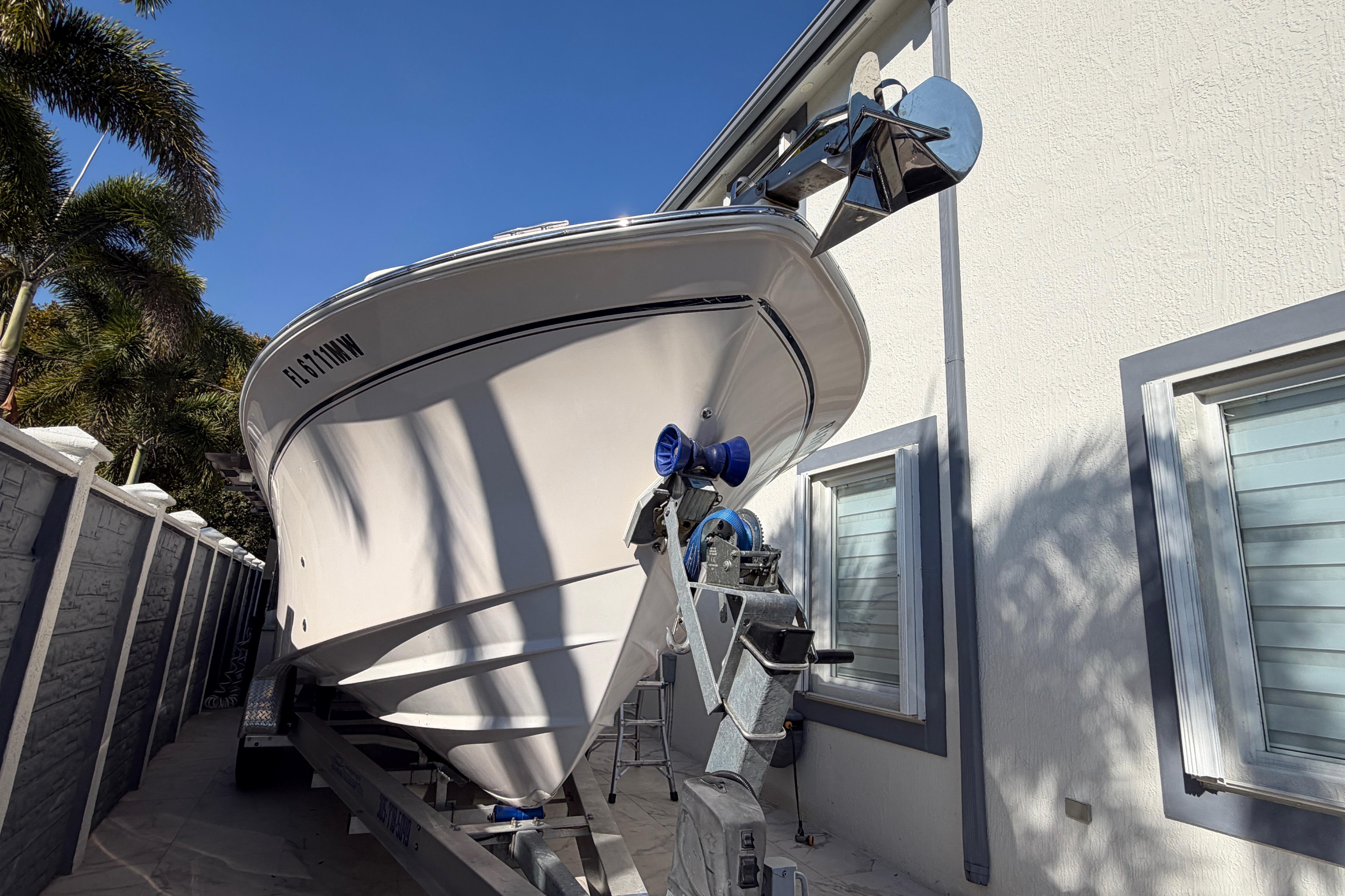 2004 Grady White 273 boat on trailer beside a house, under clear blue sky.