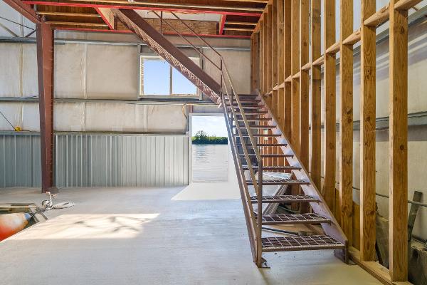 Industrial interior of 1985 Custom Larson Boathouse with metal staircase and wooden beams.