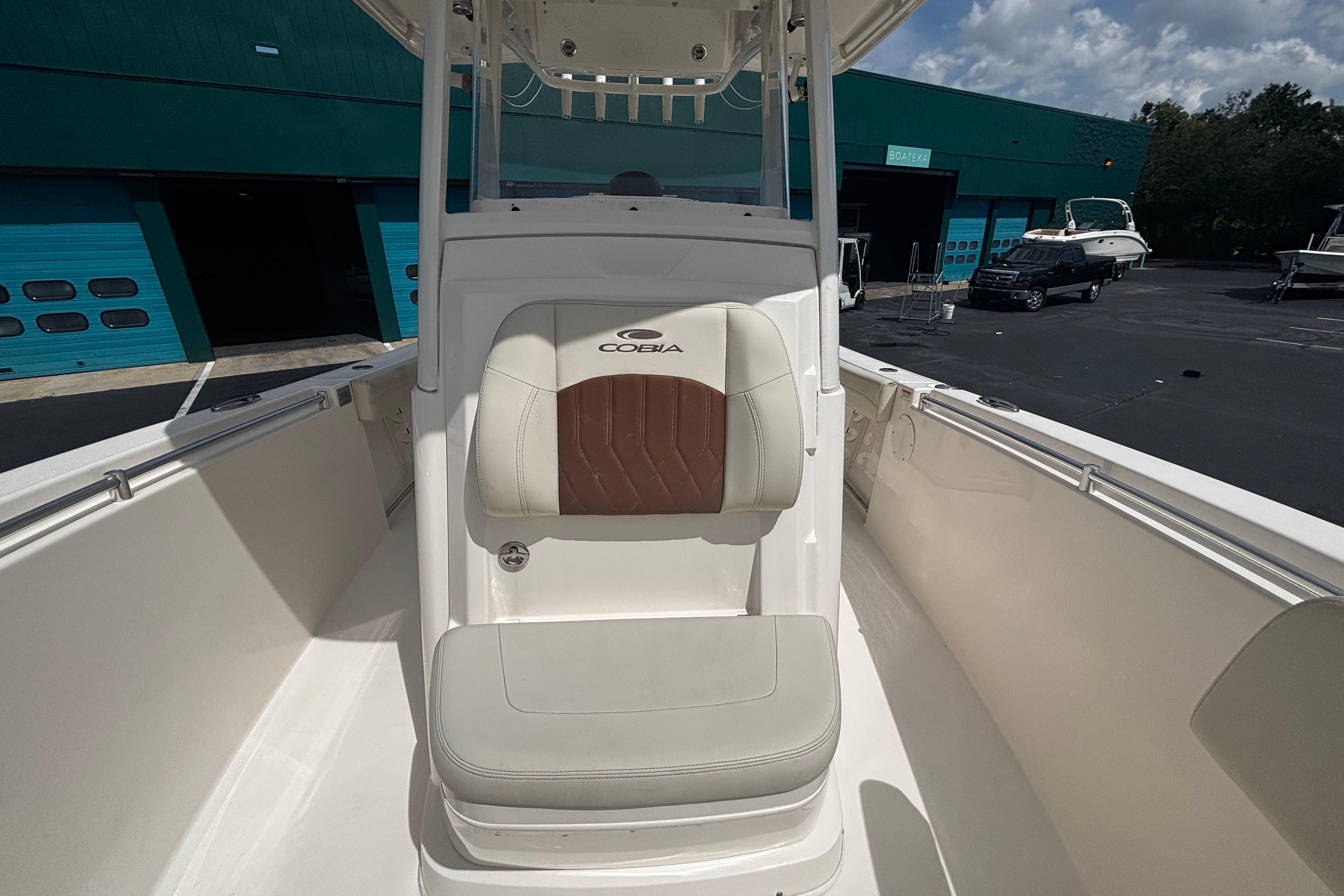 2023 Cobia 262 Center Console boat interior with cushioned seating, docked near blue garage doors.