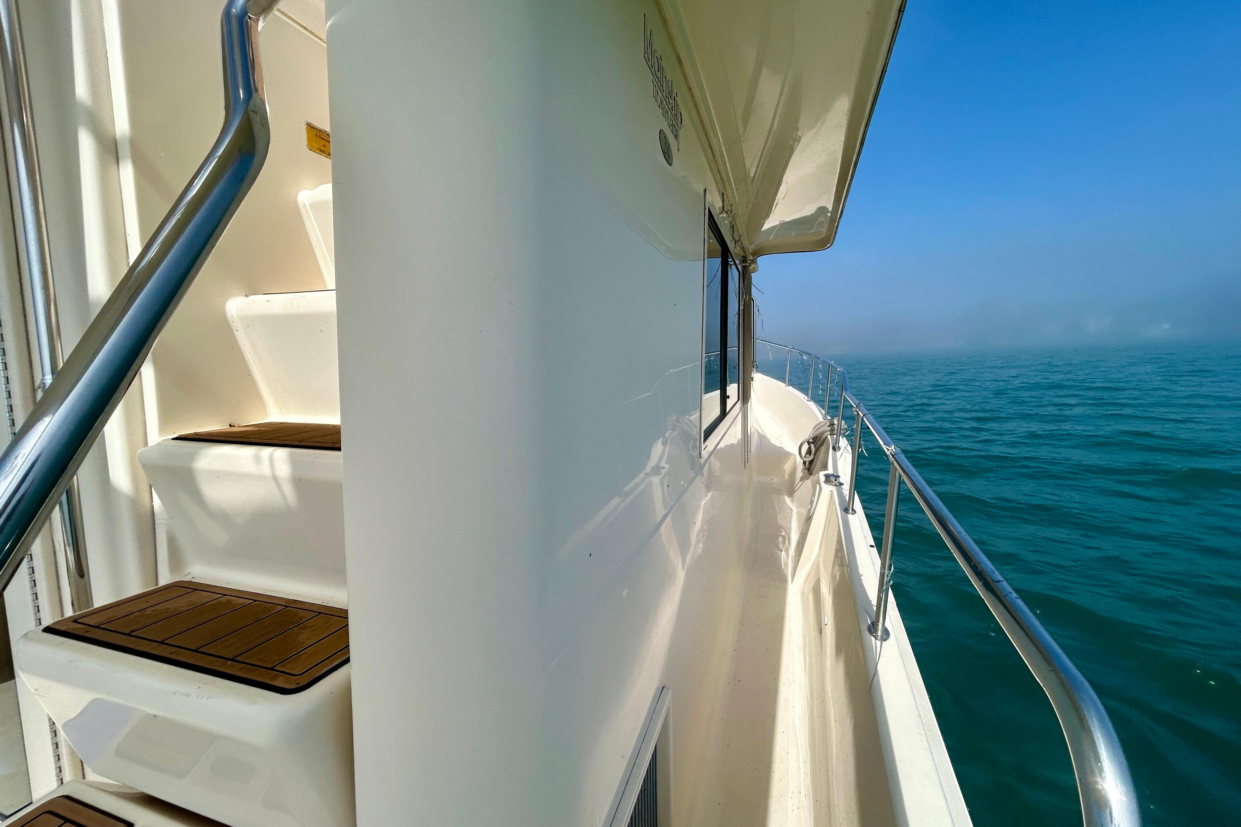 2006 Mainship 34 Trawler side deck view with ocean backdrop.