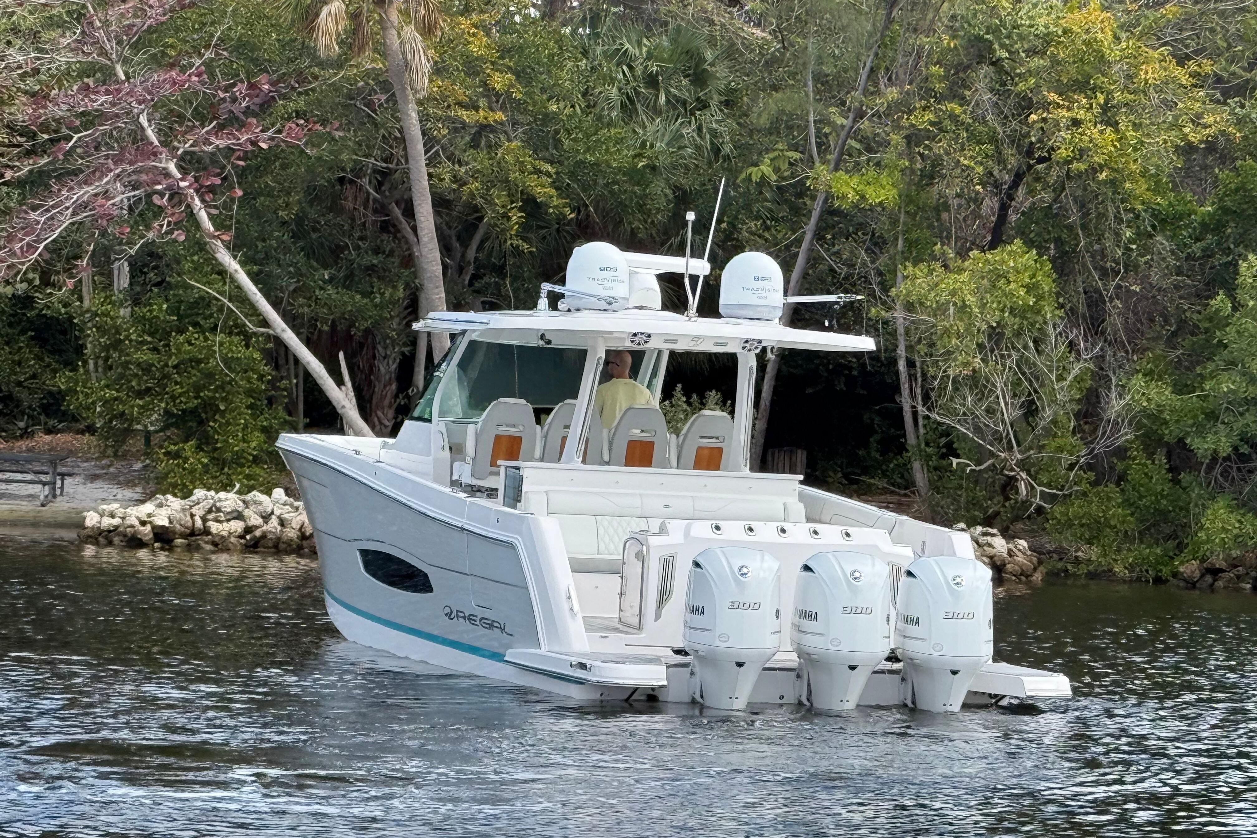 2020 Regal 38 SAV boat with four engines on a serene waterway.