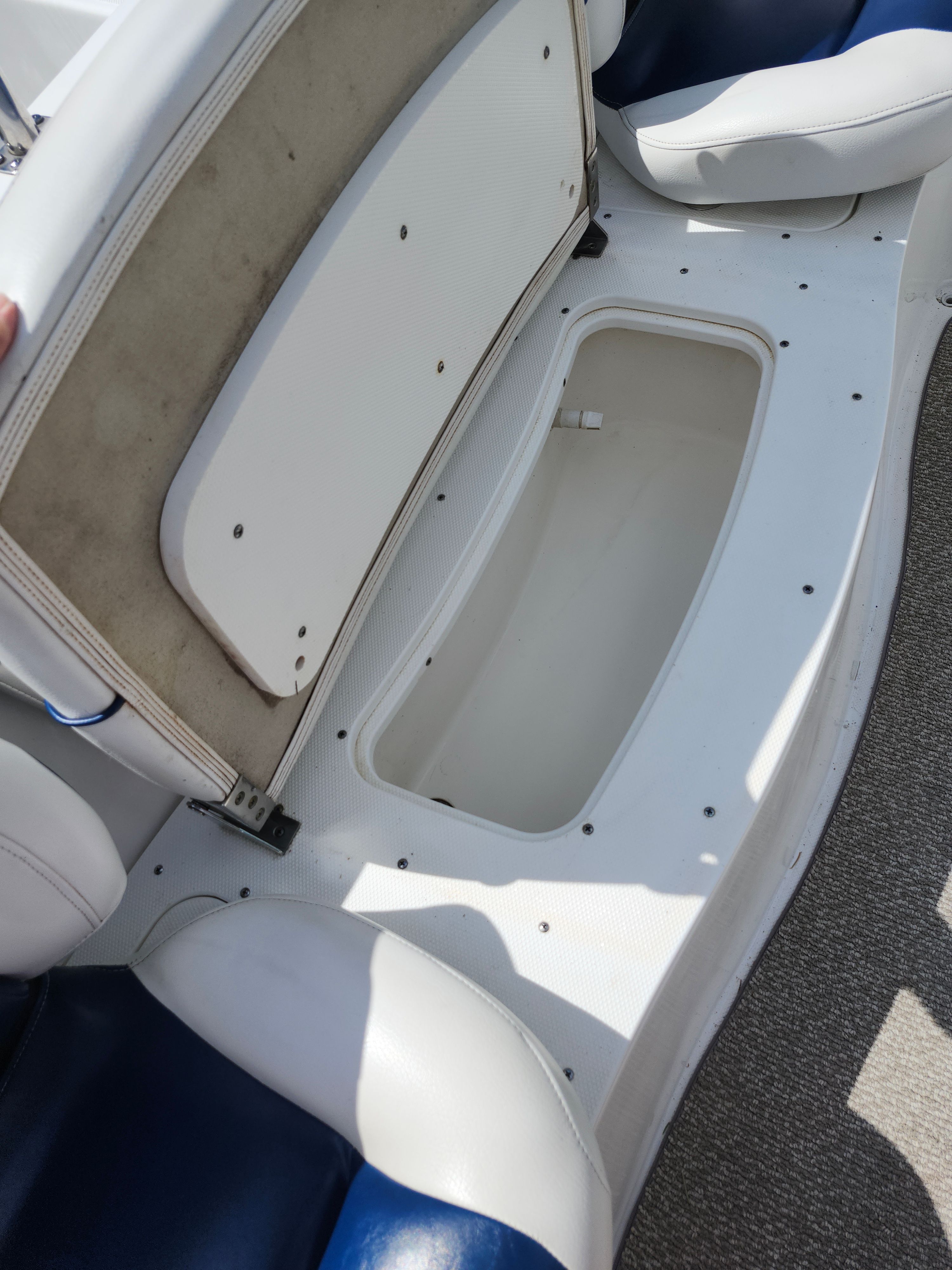 An open storage compartment on a boat with white and blue upholstery.