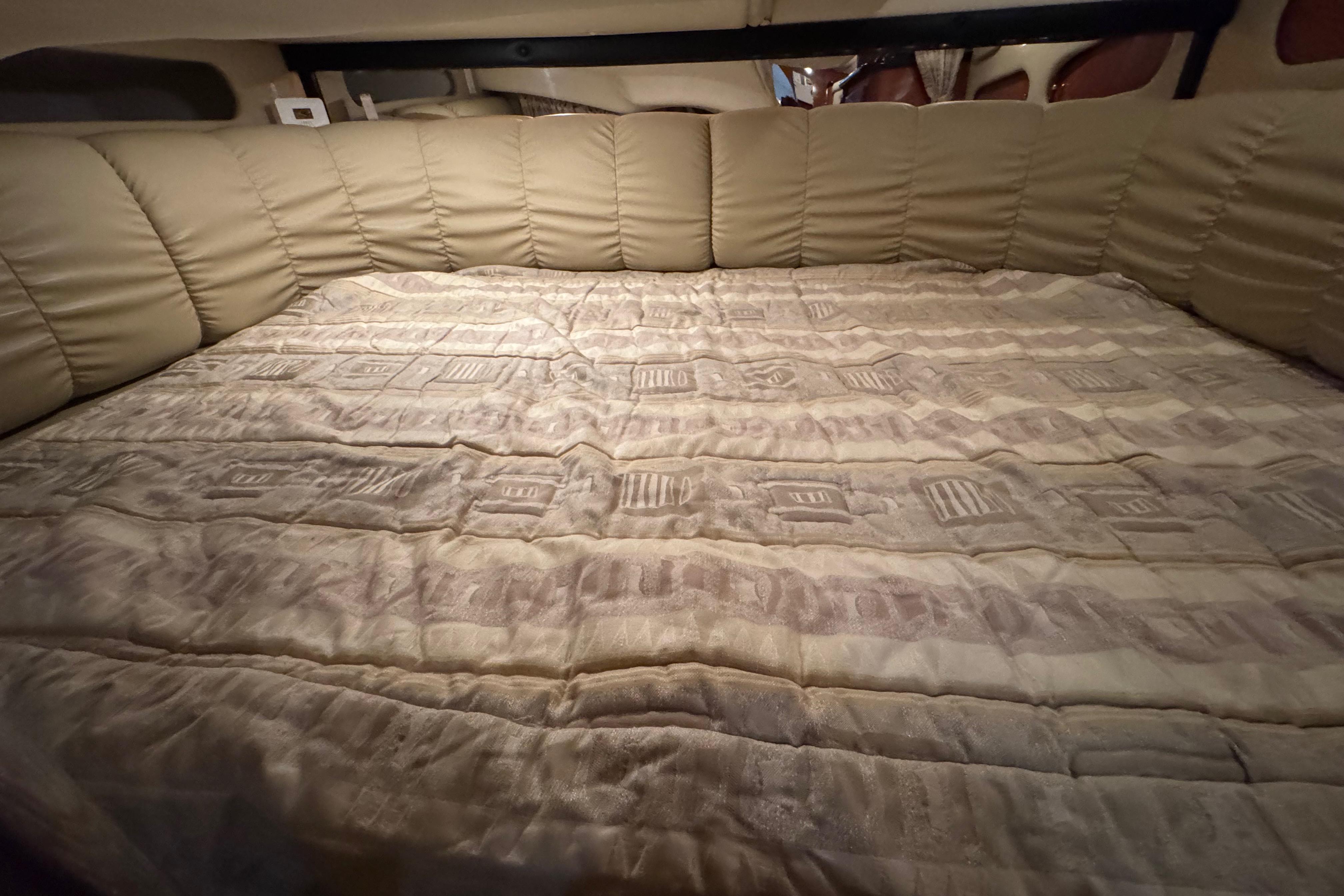 Interior cabin bed of 2004 Rinker Fiesta Vee 312 boat, featuring cushioned upholstery.
