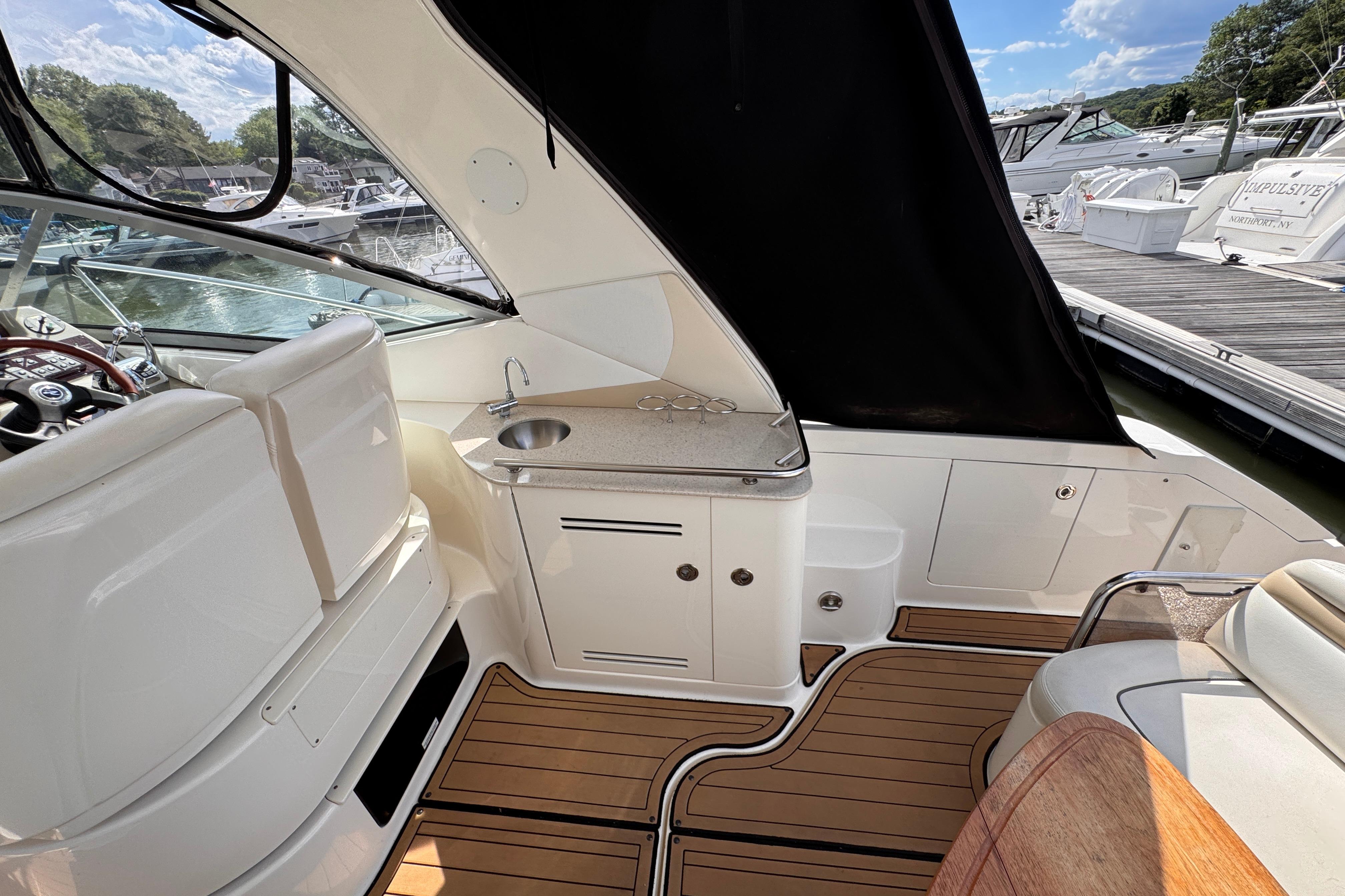 2008 Sea Ray Sundancer 350 interior with helm, sink, and wooden flooring.