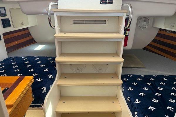 Interior of 2011 Reliance 44 yacht with wooden steps and nautical-themed bedding.