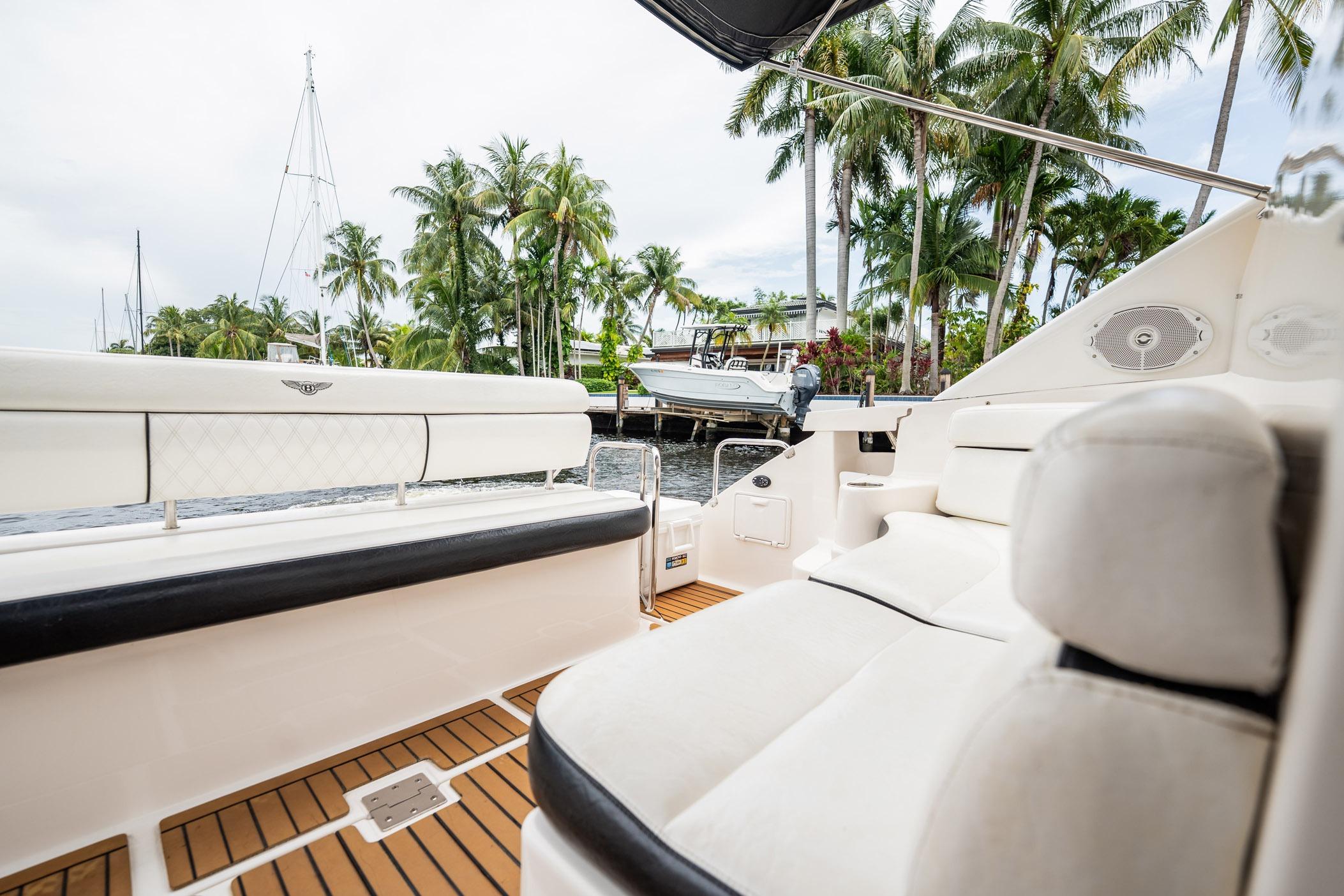 Luxurious 2008 Regal Commodore 4460 yacht interior with plush seating and tropical palm backdrop.