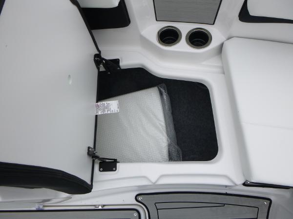 Open storage compartment in 2025 Yamaha Boats 222SD, featuring white cushioned seating and cup holders.