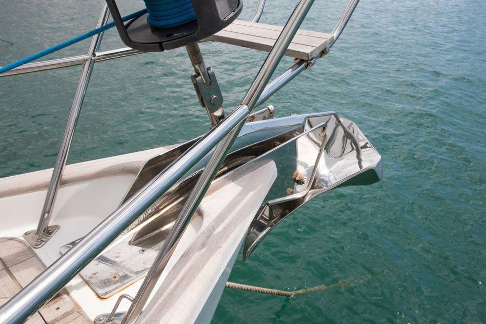 Bow of 2004 Oyster 49 yacht with anchor and railing over water.