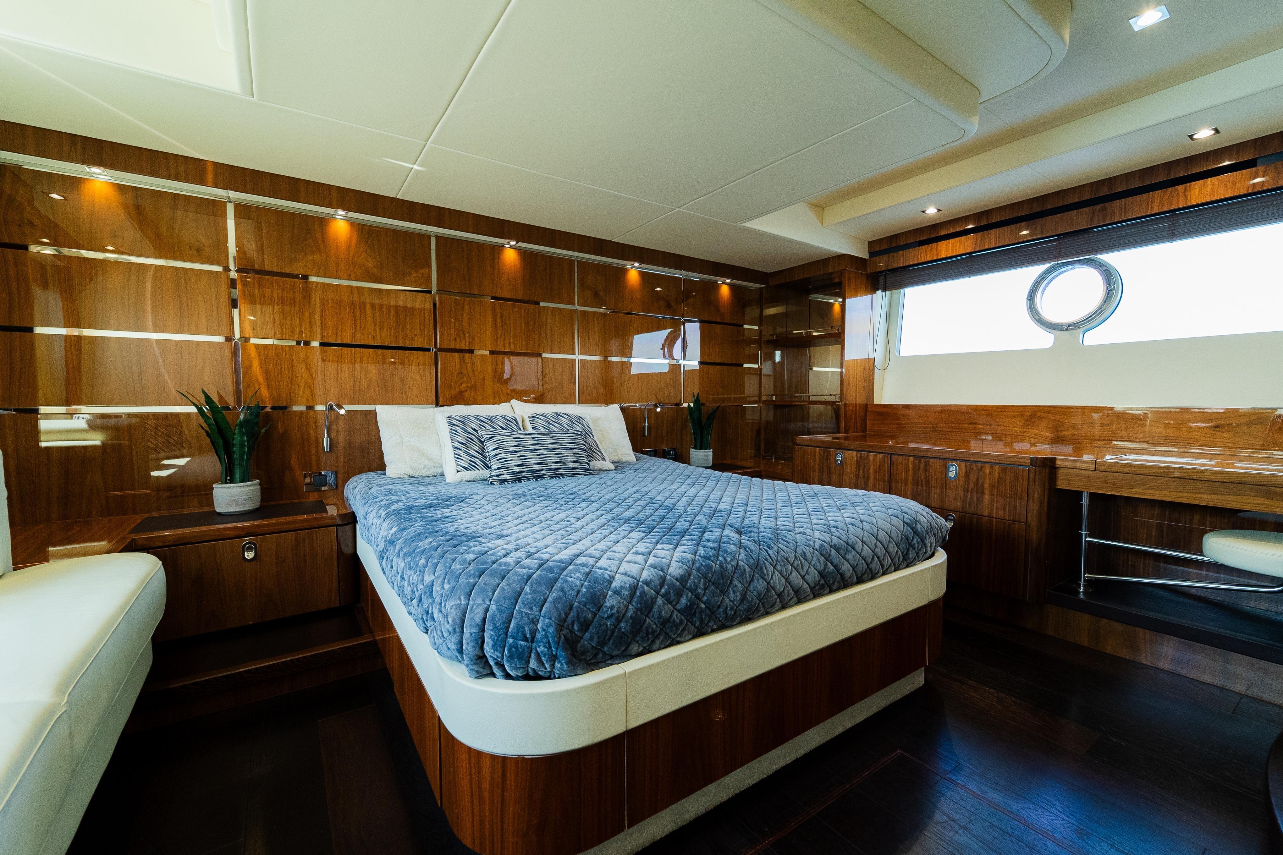 Luxurious bedroom interior of 2016 Sunseeker Manhattan 65 yacht with elegant wood paneling.