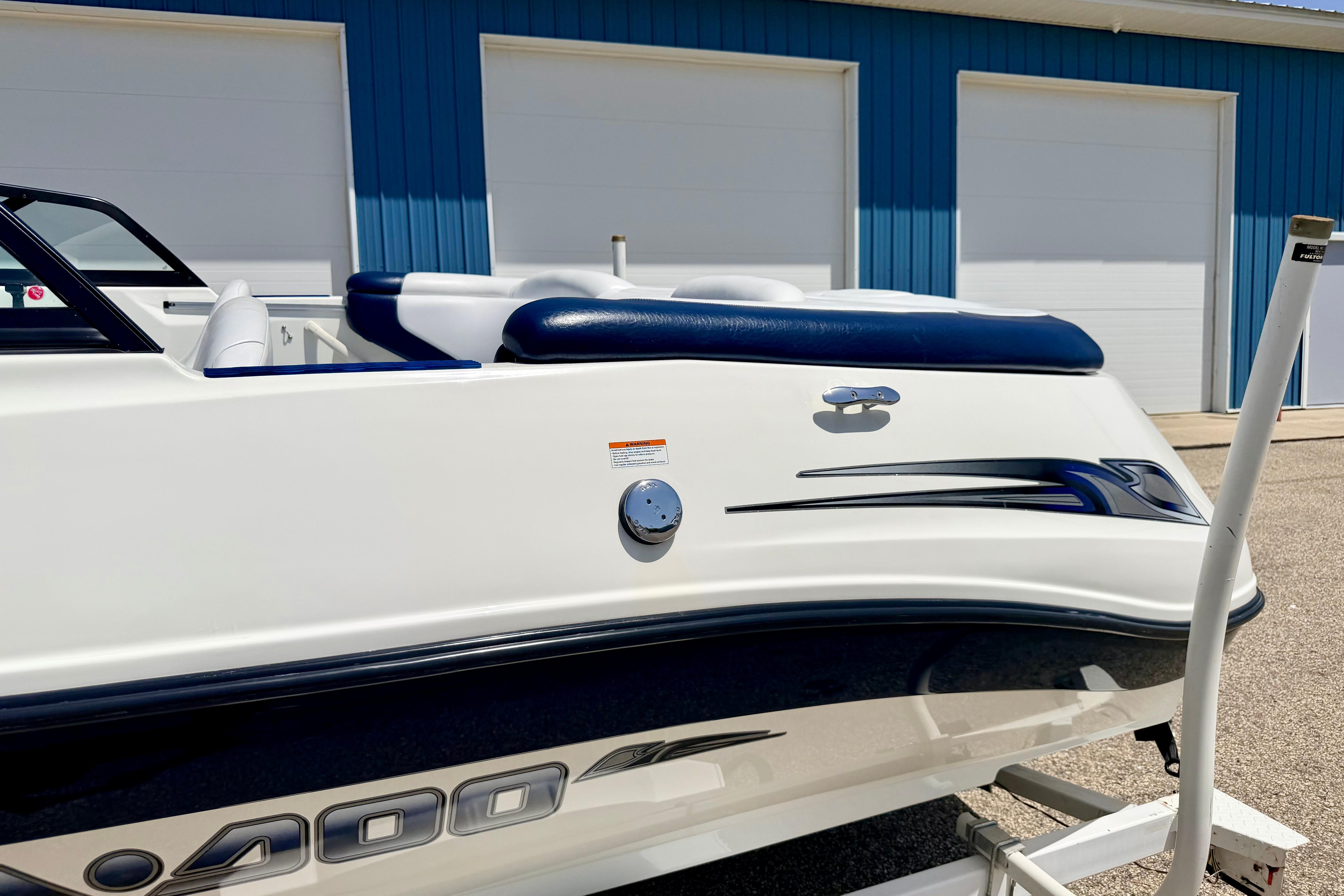 2004 Bombardier SEADOO Utopia 185 boat, white with blue accents, parked near blue building.