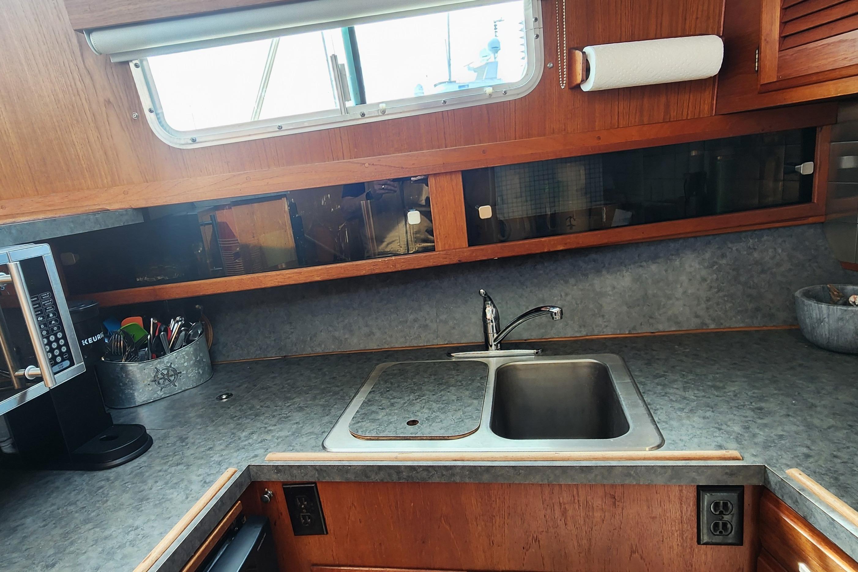 1981 Tollycraft 43 yacht kitchen with sink, countertop, and window view.