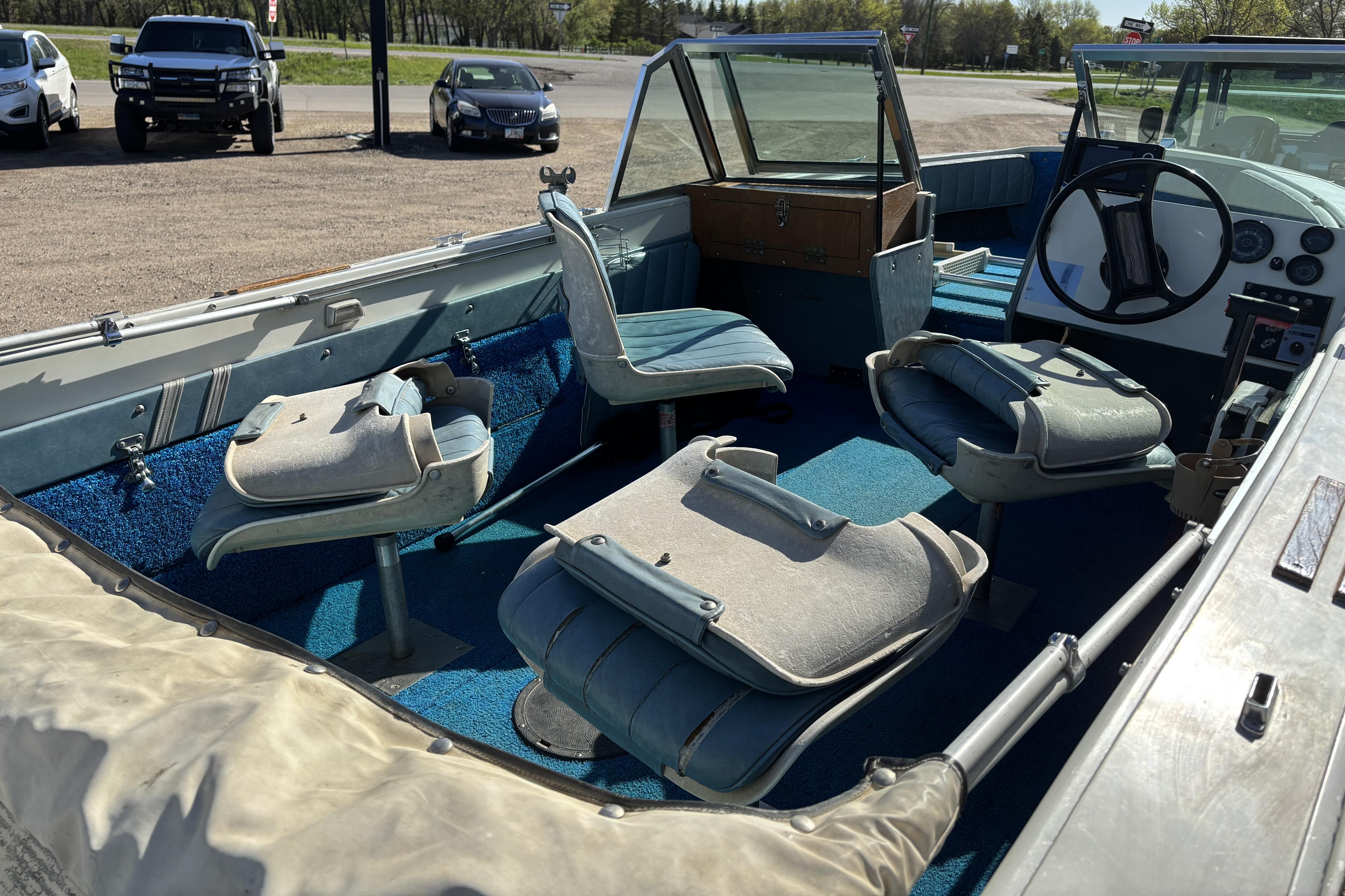 1983 Crestliner 16 boat interior with blue carpet and swivel seats.