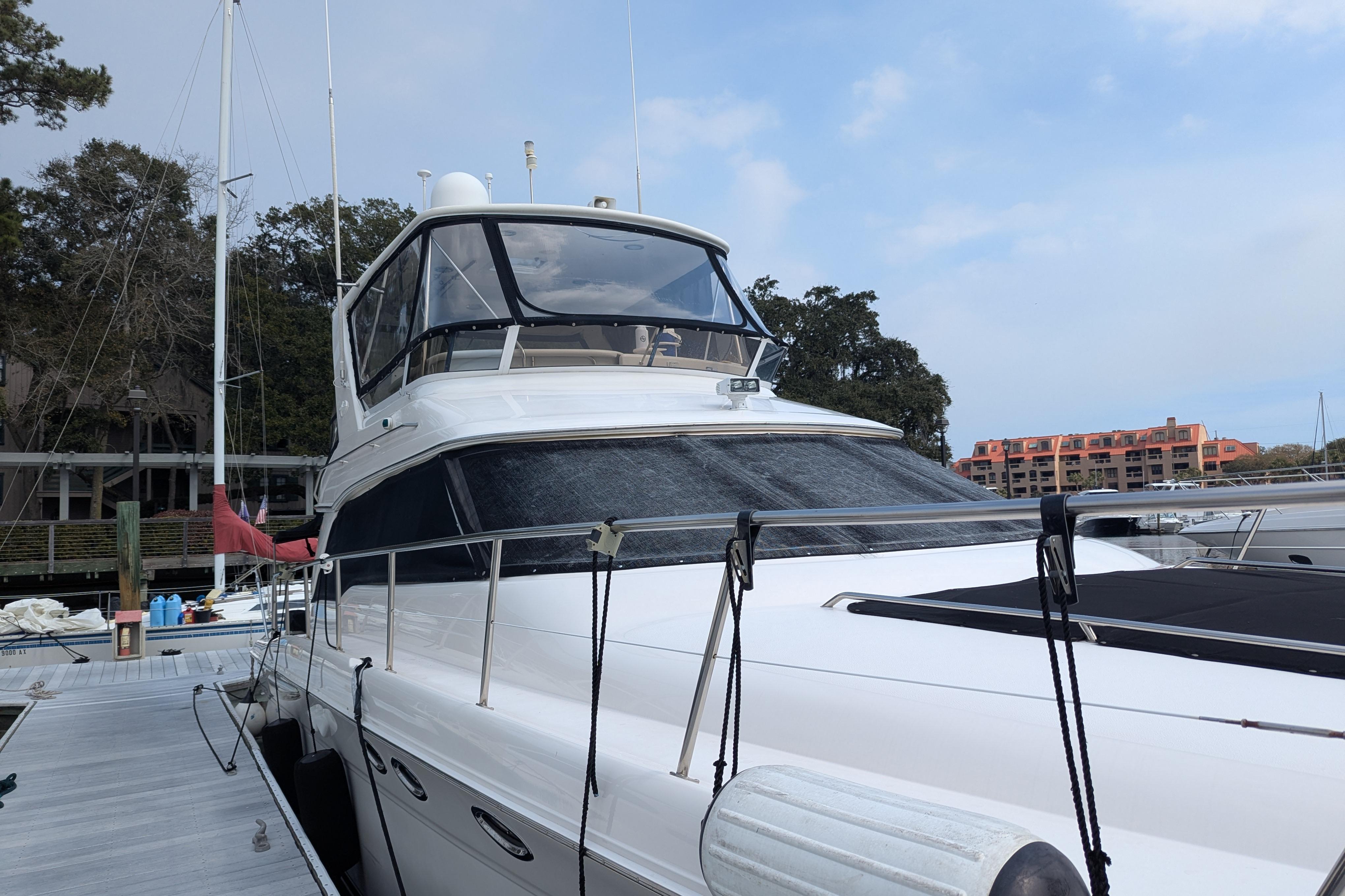 1998 Sea Ray 480 Sedan Bridge yacht docked at marina, clear sky background.
