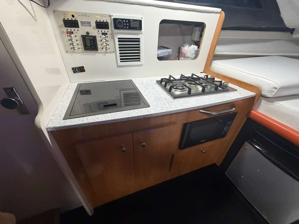 The galley of a 2001 Bayliner 2452 Ciera Classic with stove, sink, and cabinets.