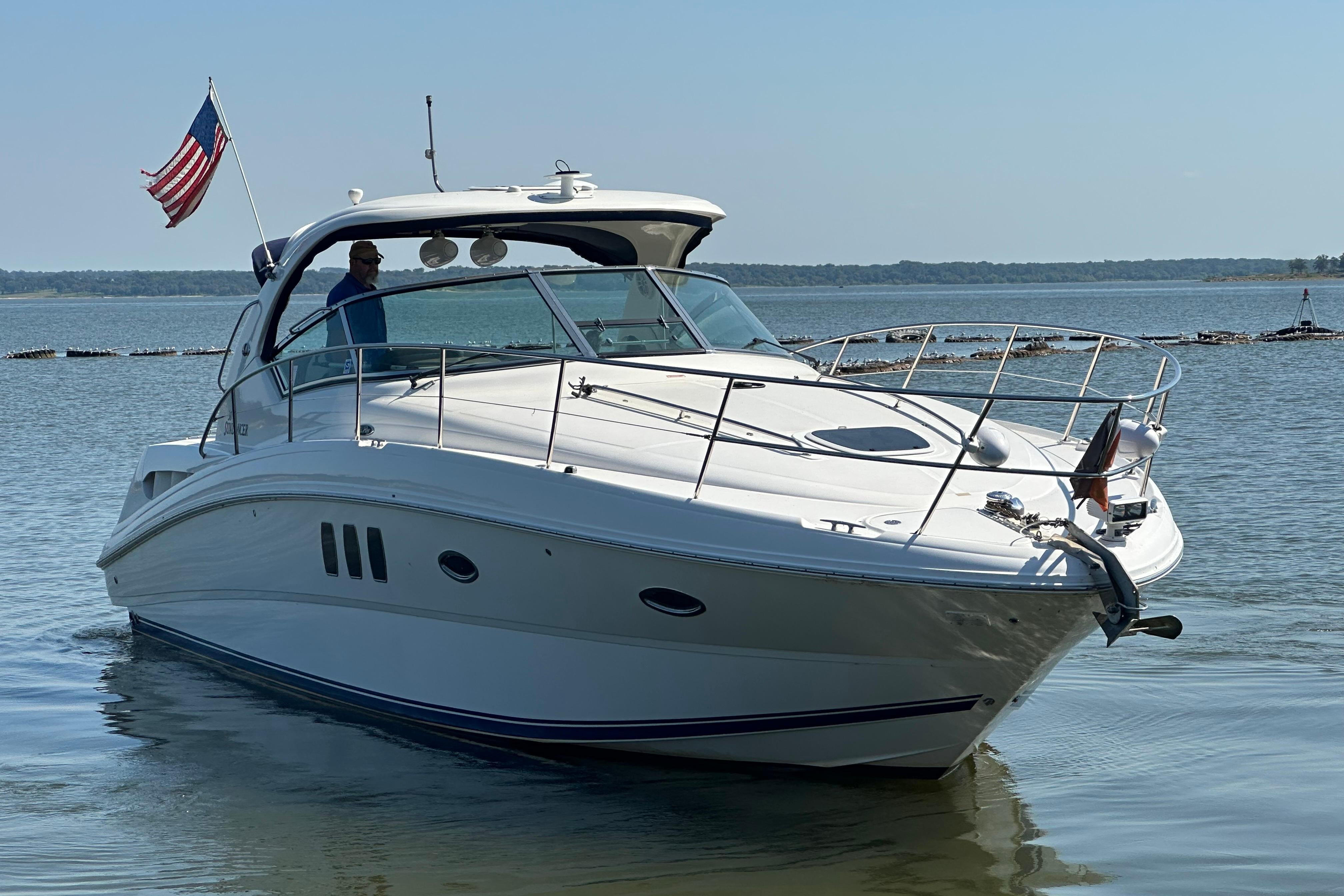 2007 Sea Ray 38 Sundancer yacht cruising on calm waters with American flag.