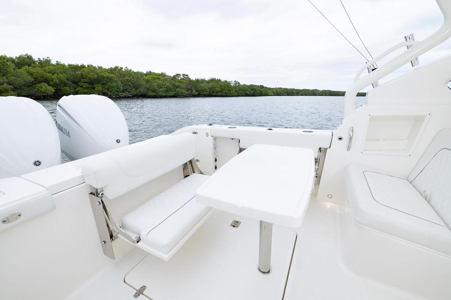 Manufacturer Provided Image: 2026 Pursuit DC 286 Dual Console boat interior with seating and table, near water and greenery.