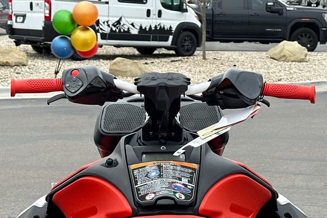 Handlebars of a Sea-Doo PWC with red grips and colorful balloons in the background.
