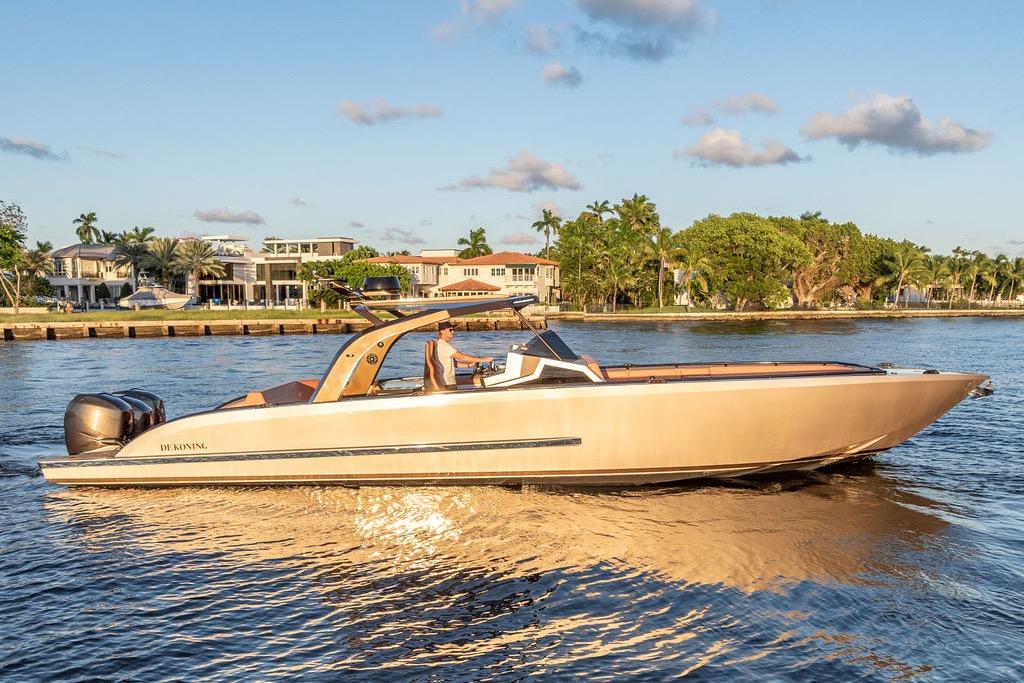 2023 DeKoning 43 luxury boat cruising on a sunny waterfront.