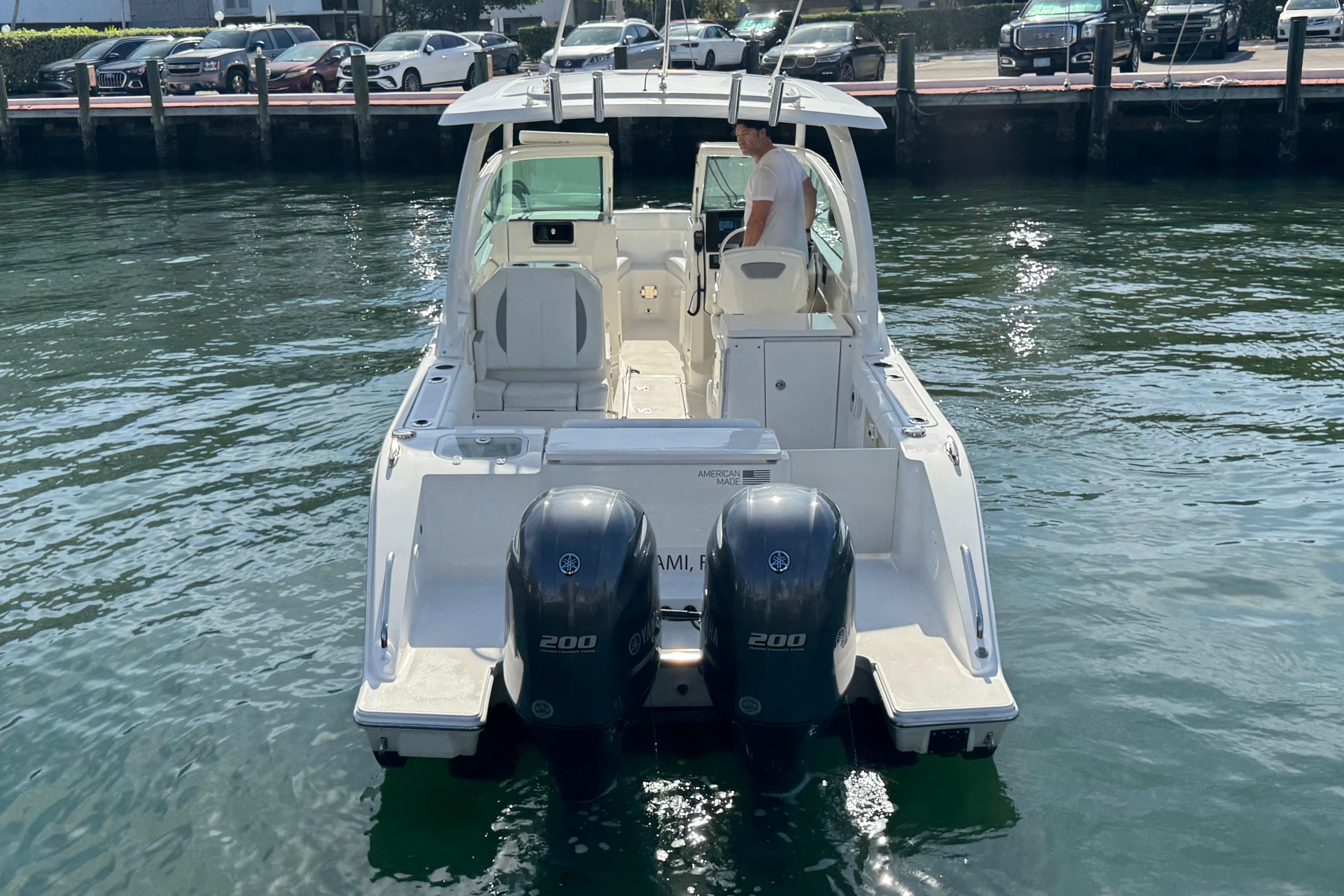2022 Pursuit DC 266 Dual Console boat on water, rear view with twin engines.