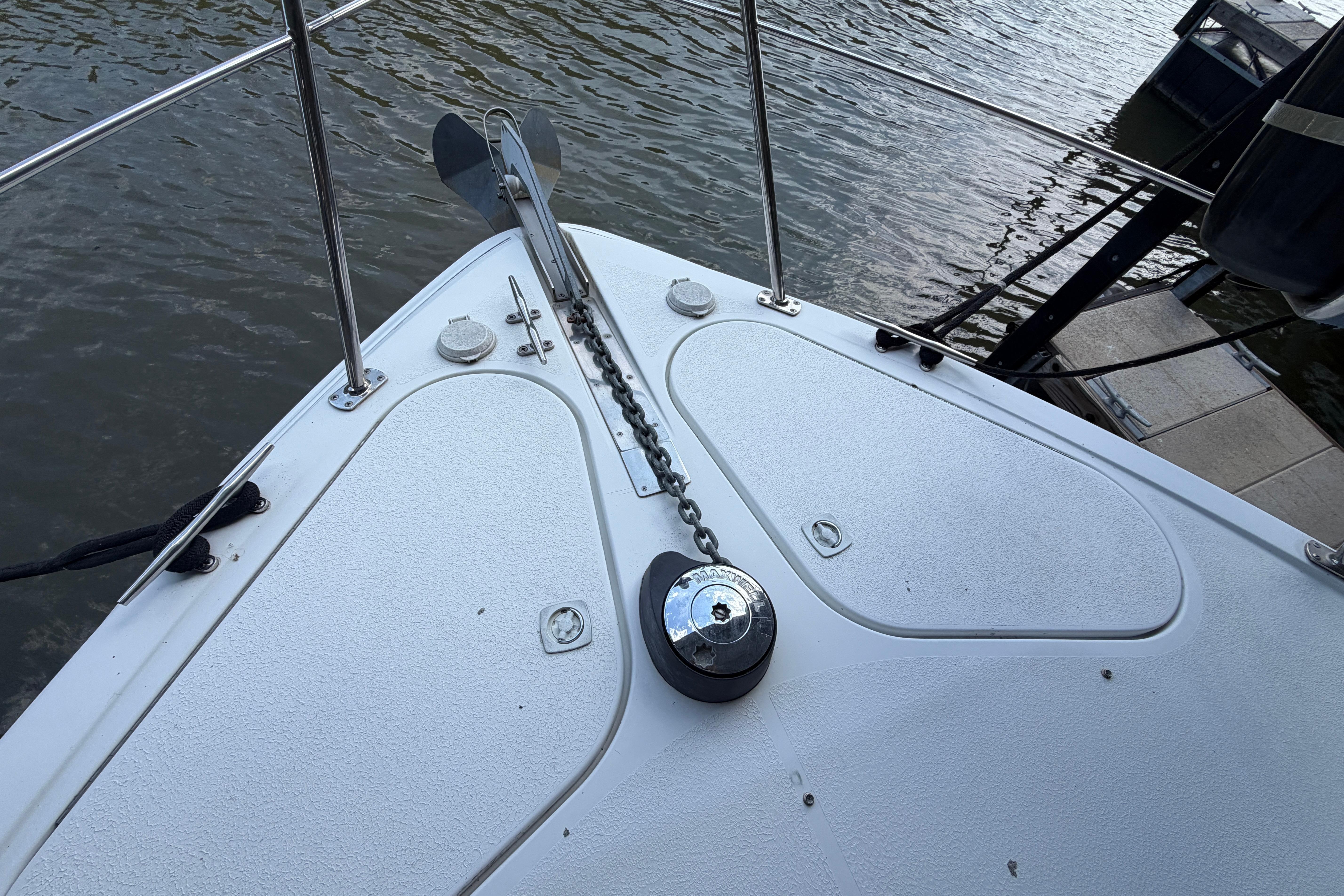 Bow of 2000 Carver 350 Mariner with anchor chain, docked on calm water.