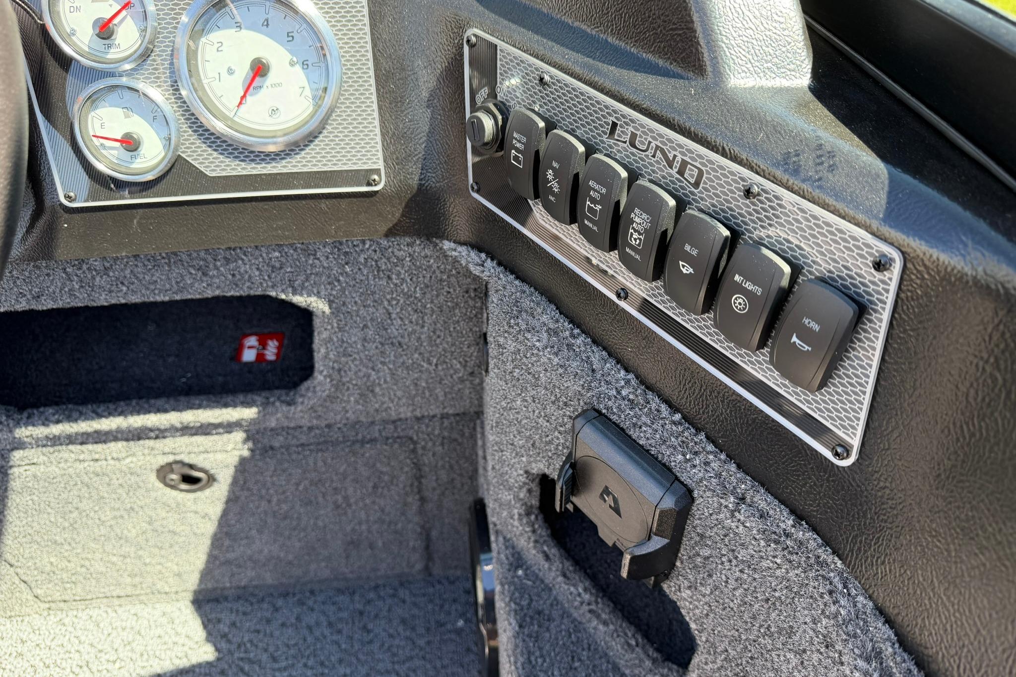 Dashboard controls of 2027 Lund 1775 Impact XS Sport boat, featuring gauges and switches.
