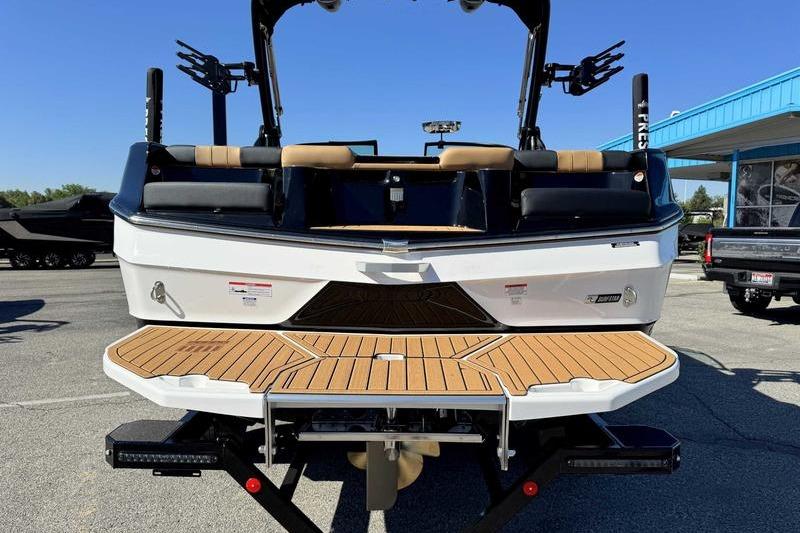 2026 MasterCraft XT22 boat rear view with teak swim platform and wakeboard racks.