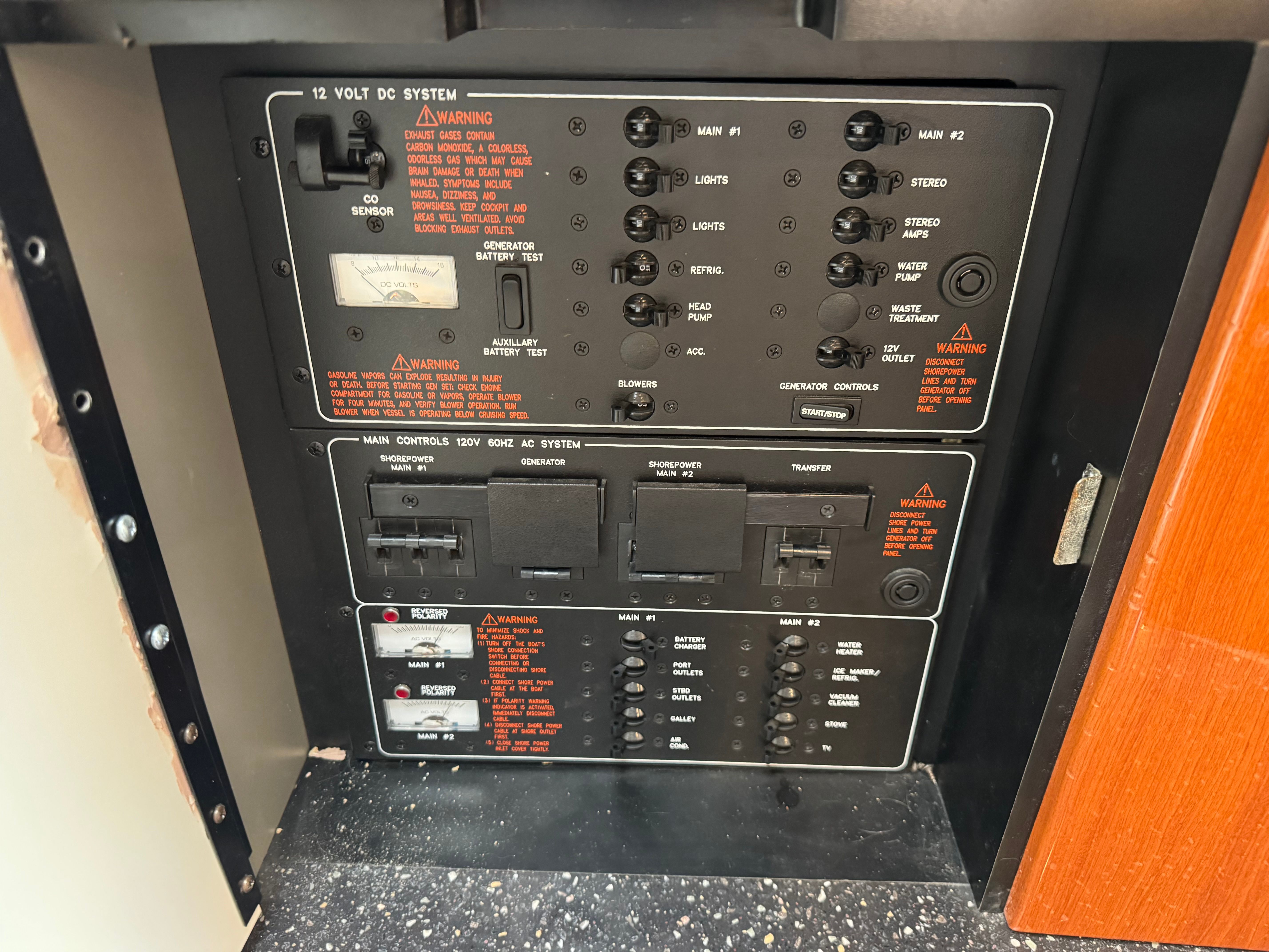 Electrical control panel system with warning labels and switches inside a boat.