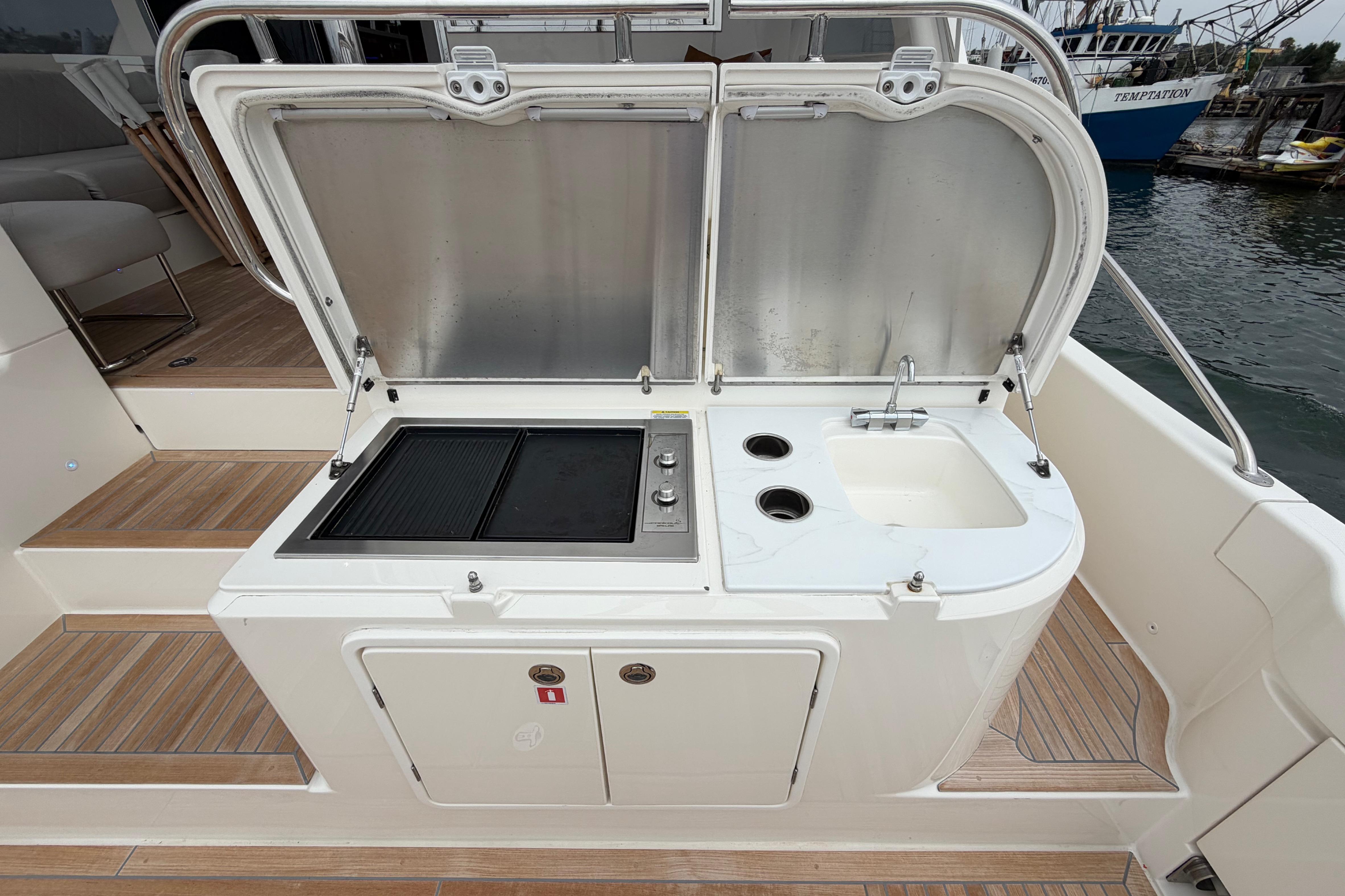 Outdoor kitchen on 2023 Riviera 645 SUV yacht with grill and sink.