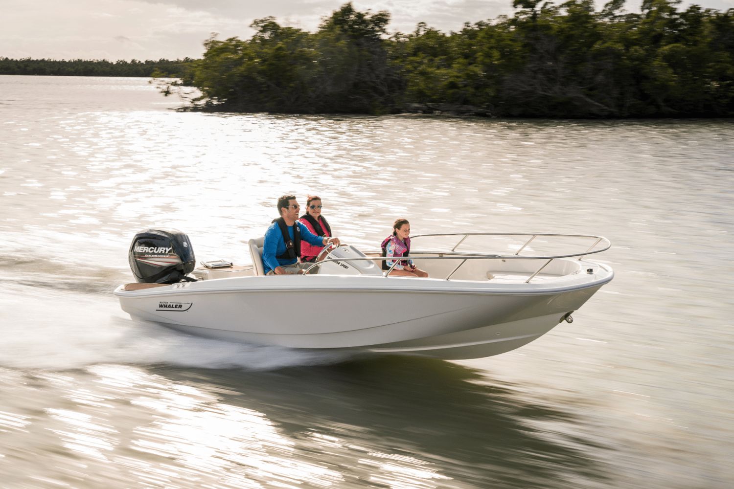 A Boston Whaler 160 Super Sport speeds across the water with three people on board.